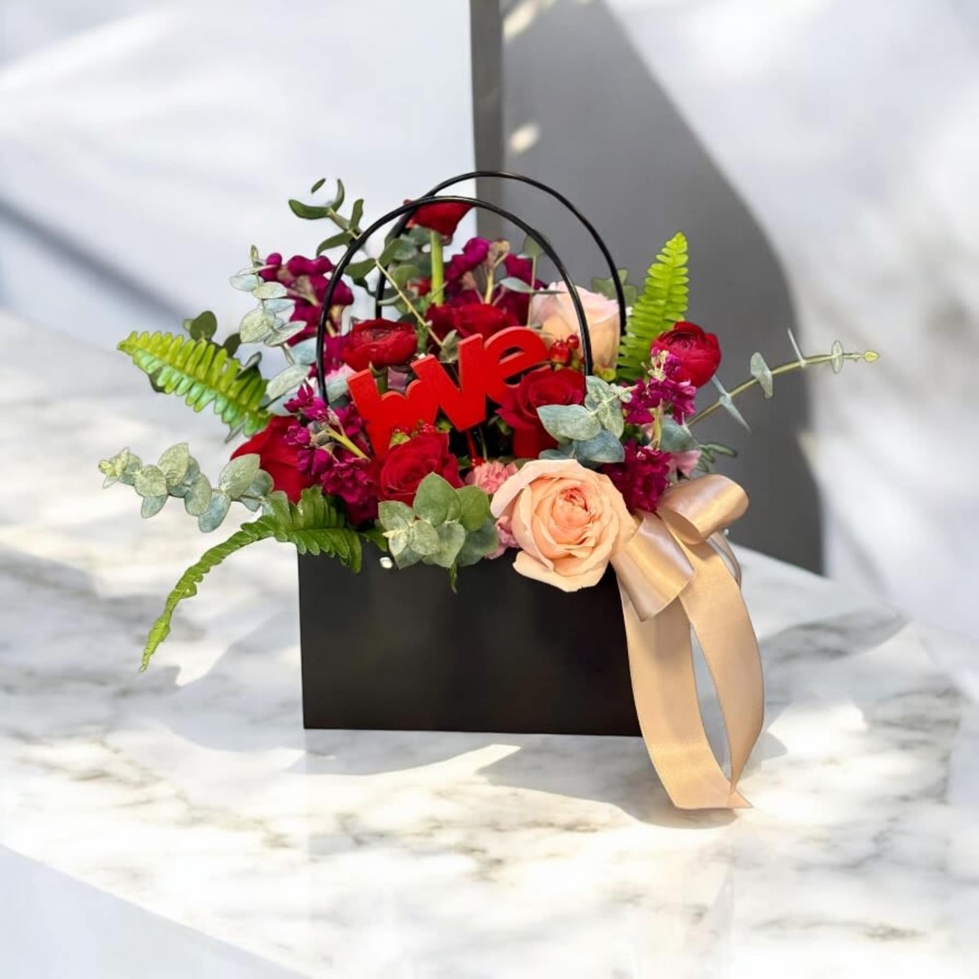 Black gift bag with red and peach roses and a red "love" sign