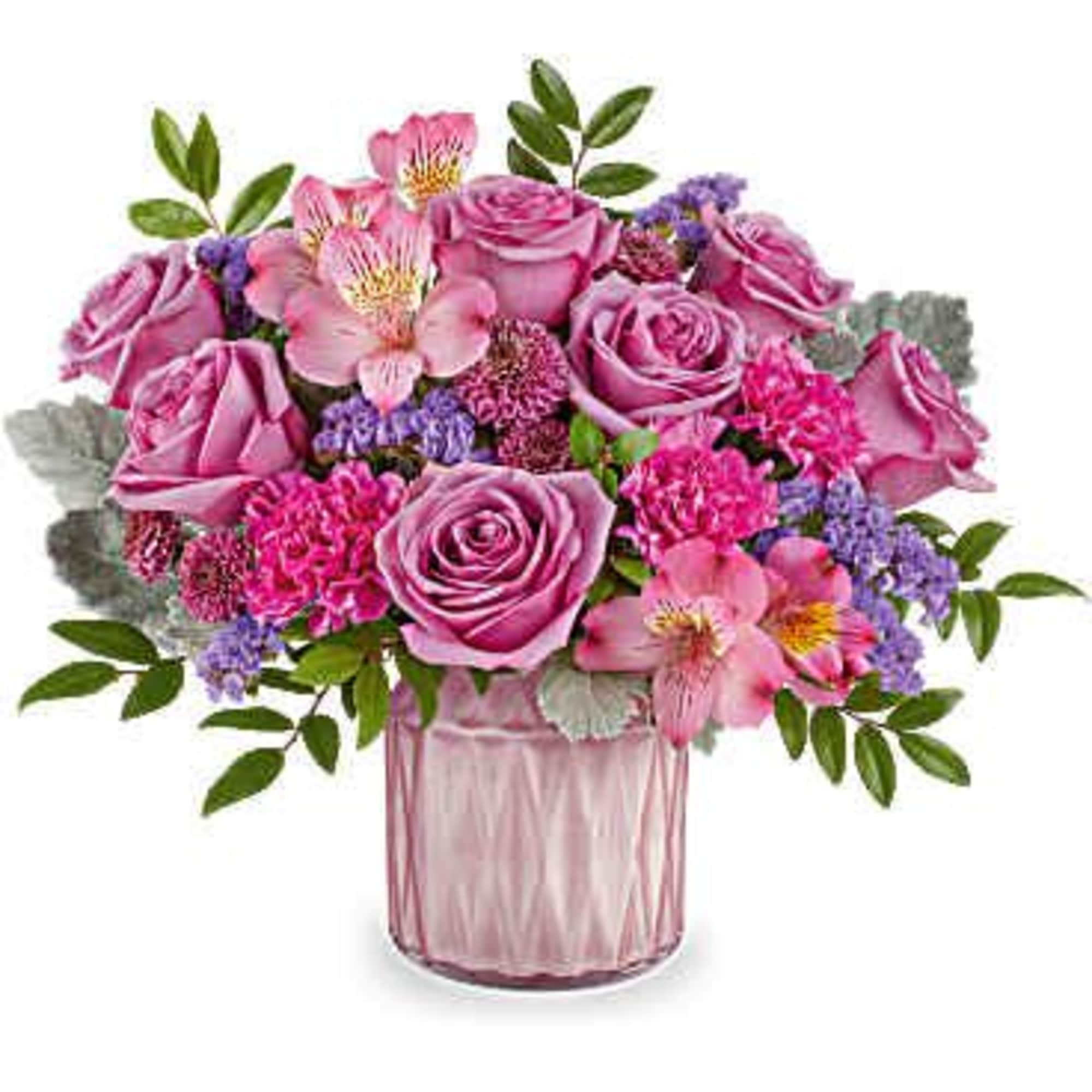 Pink roses and mixed blooms arranged in a pink glass vase
