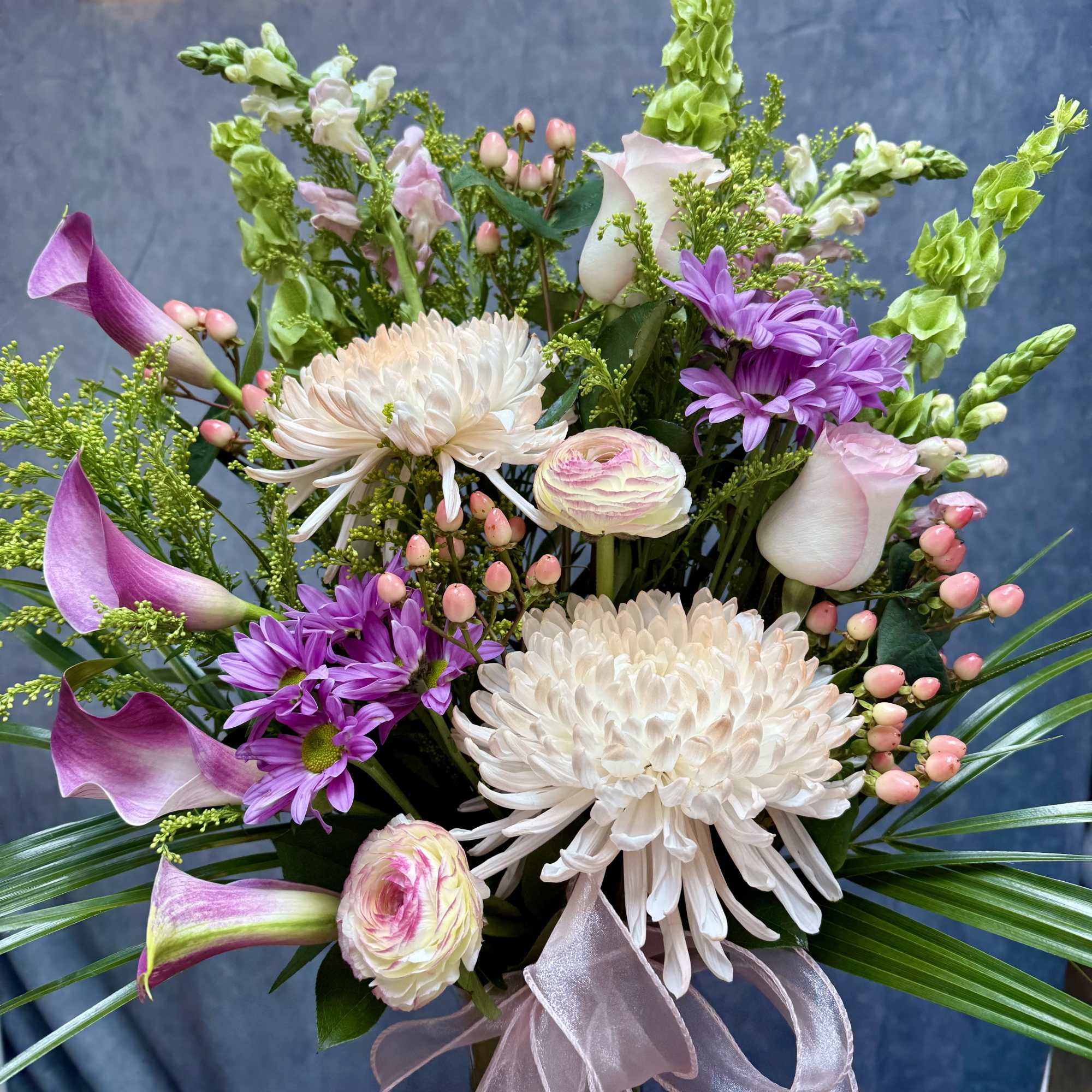 A stunning blend of elegant Calla lilies, lush mums, and delicate ranunculus