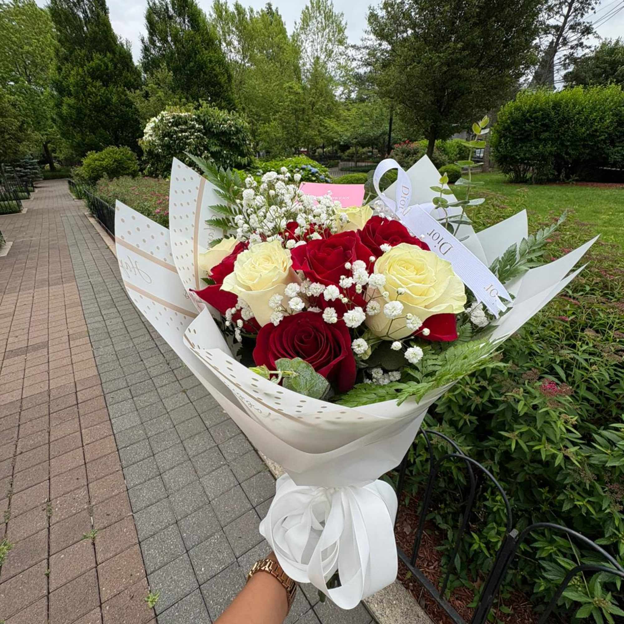 Bouquet of red and cream roses wrapped in white paper with a ribbon