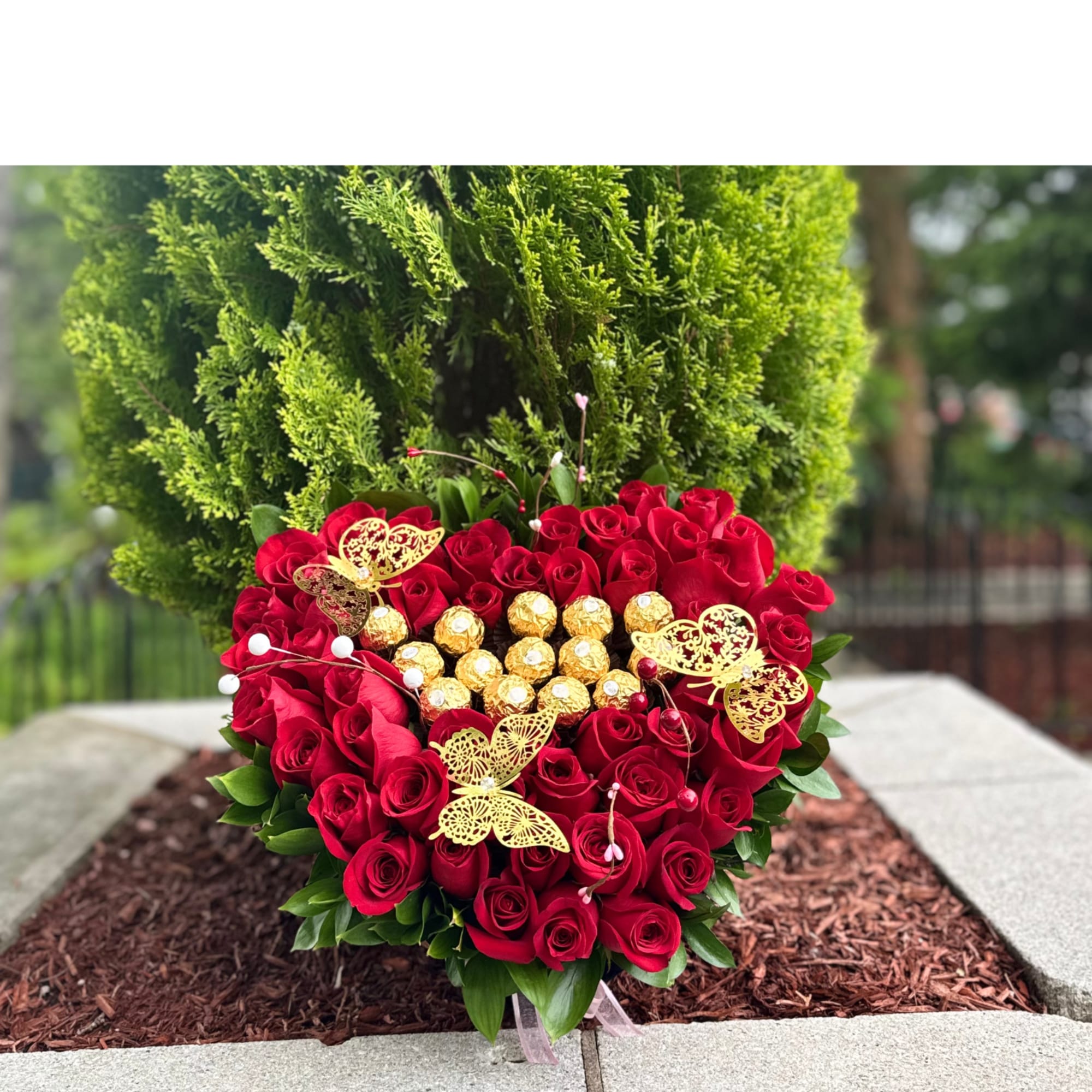 Heart-shaped bouquet of red roses with gold chocolates and butterfly picks