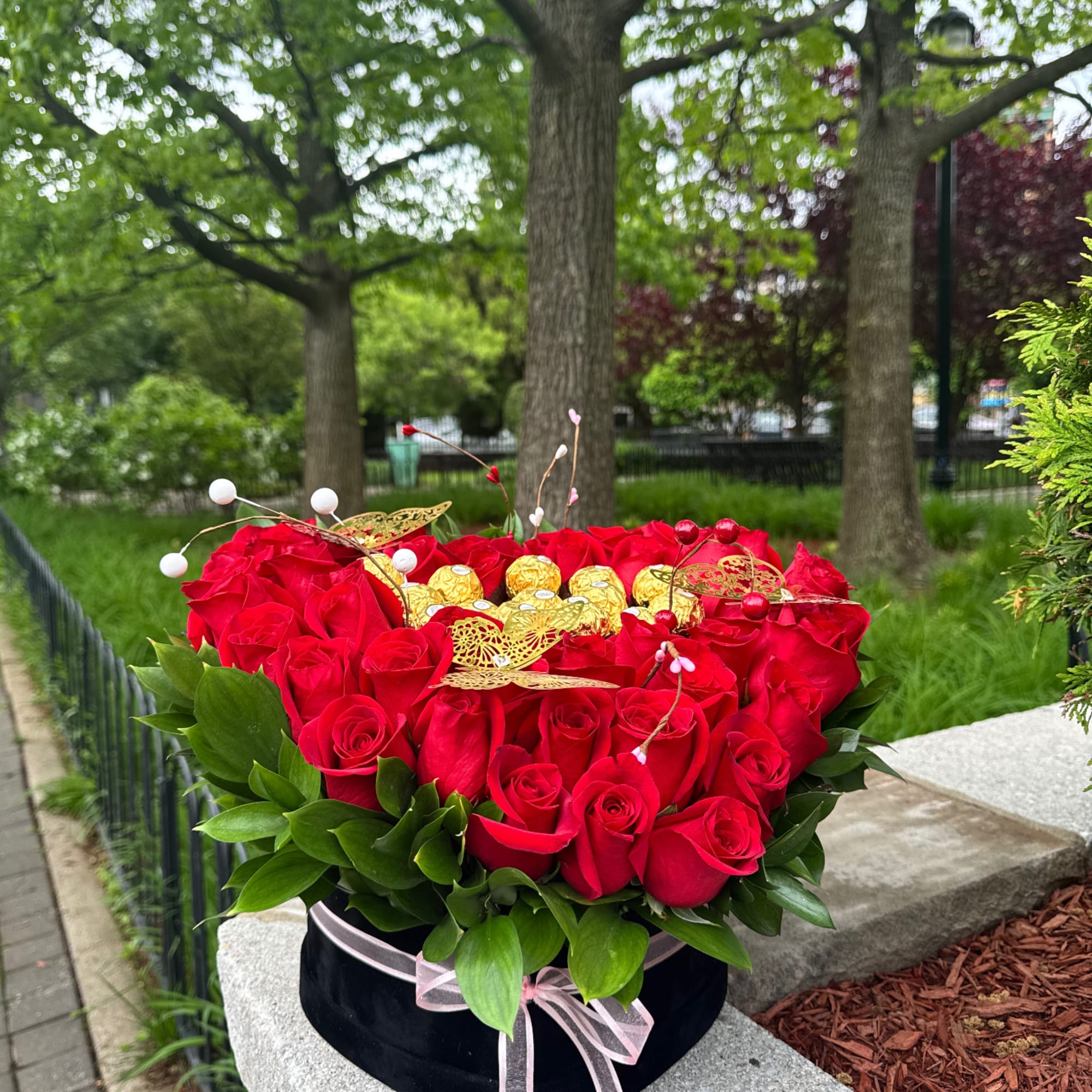 Heart-shaped box of red roses with gold chocolates and a pink ribbon