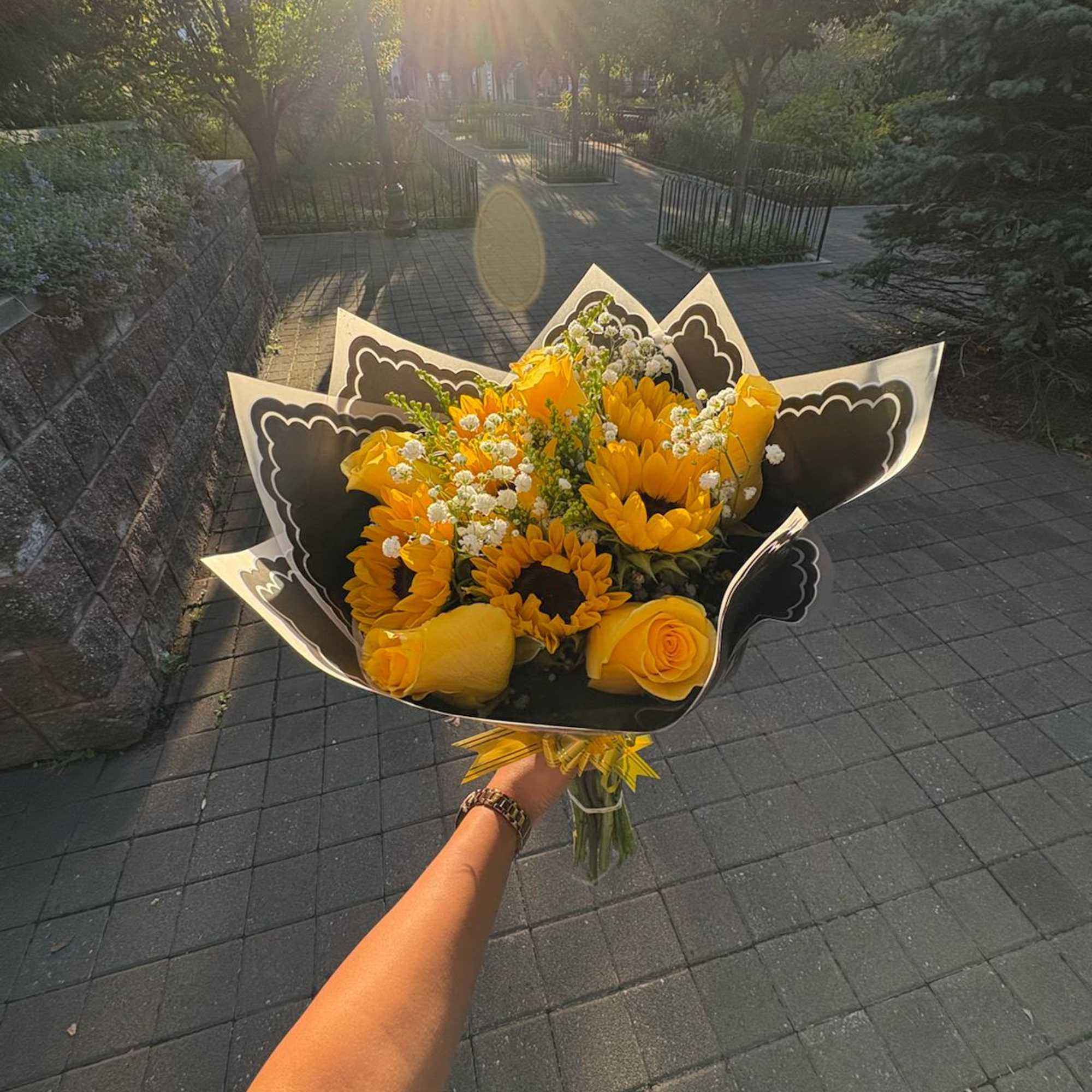 Bouquet of yellow sunflowers and roses wrapped in black paper
