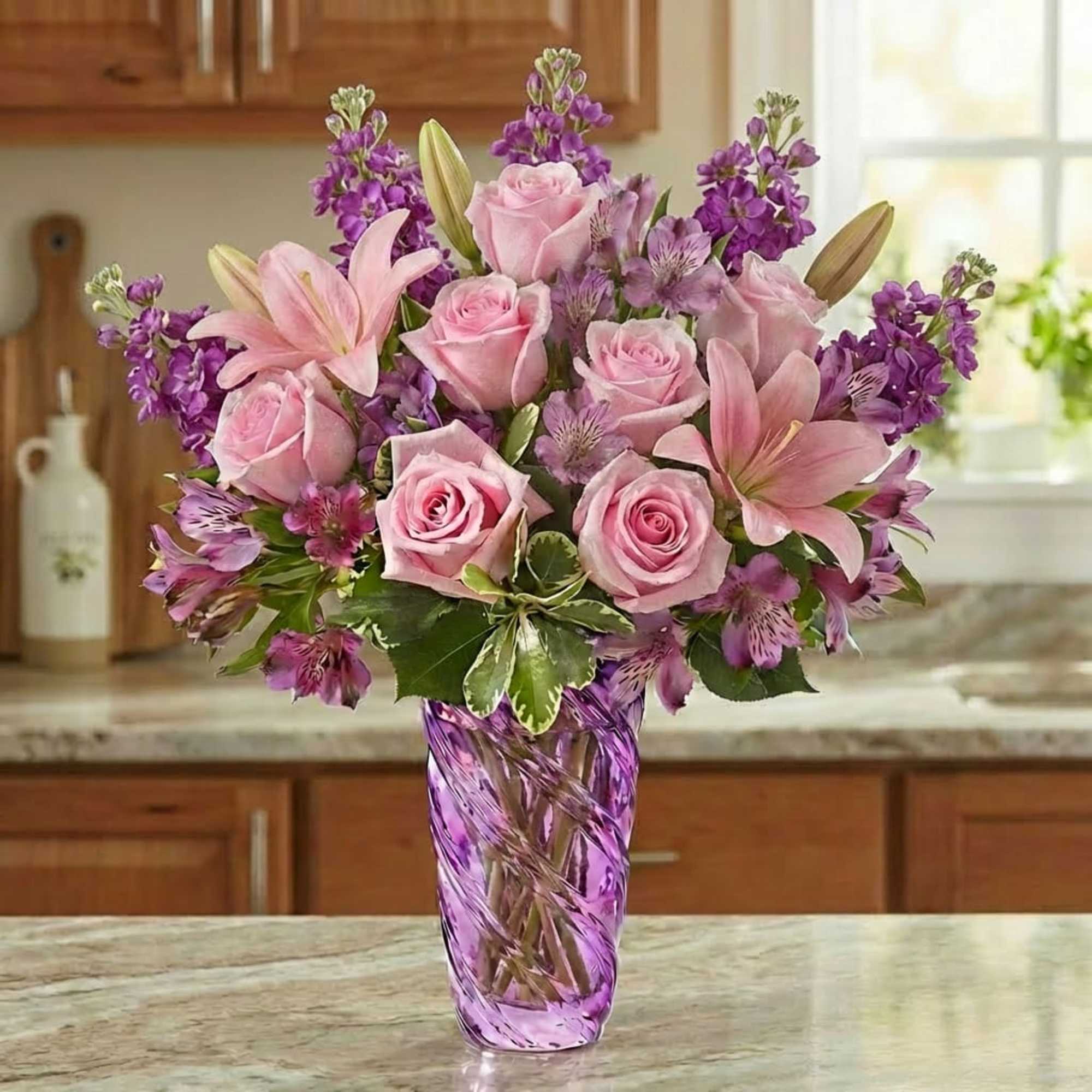 Pink roses and lilies in a purple glass vase