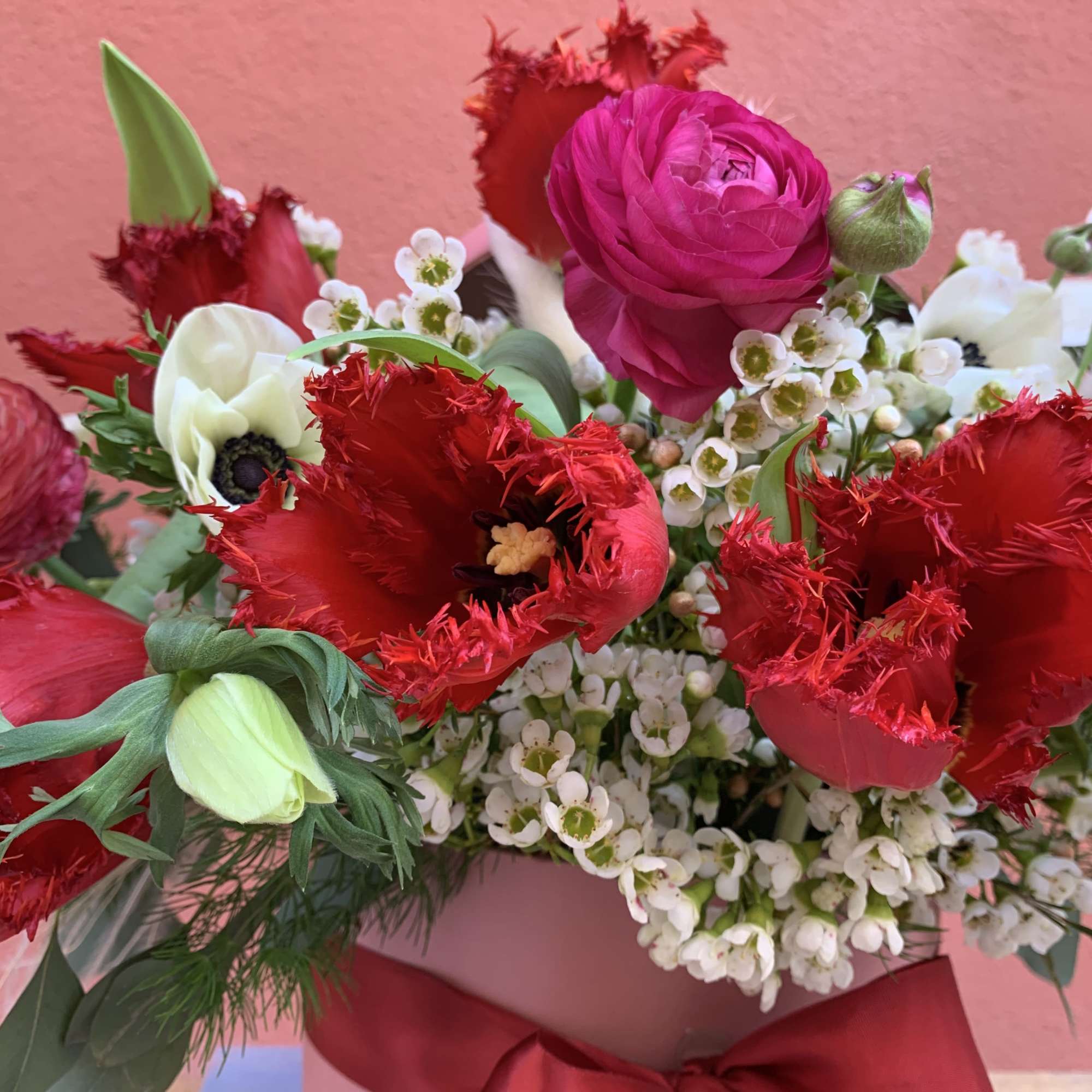Bouquet of red and pink flowers in a pink box with a red ribbon