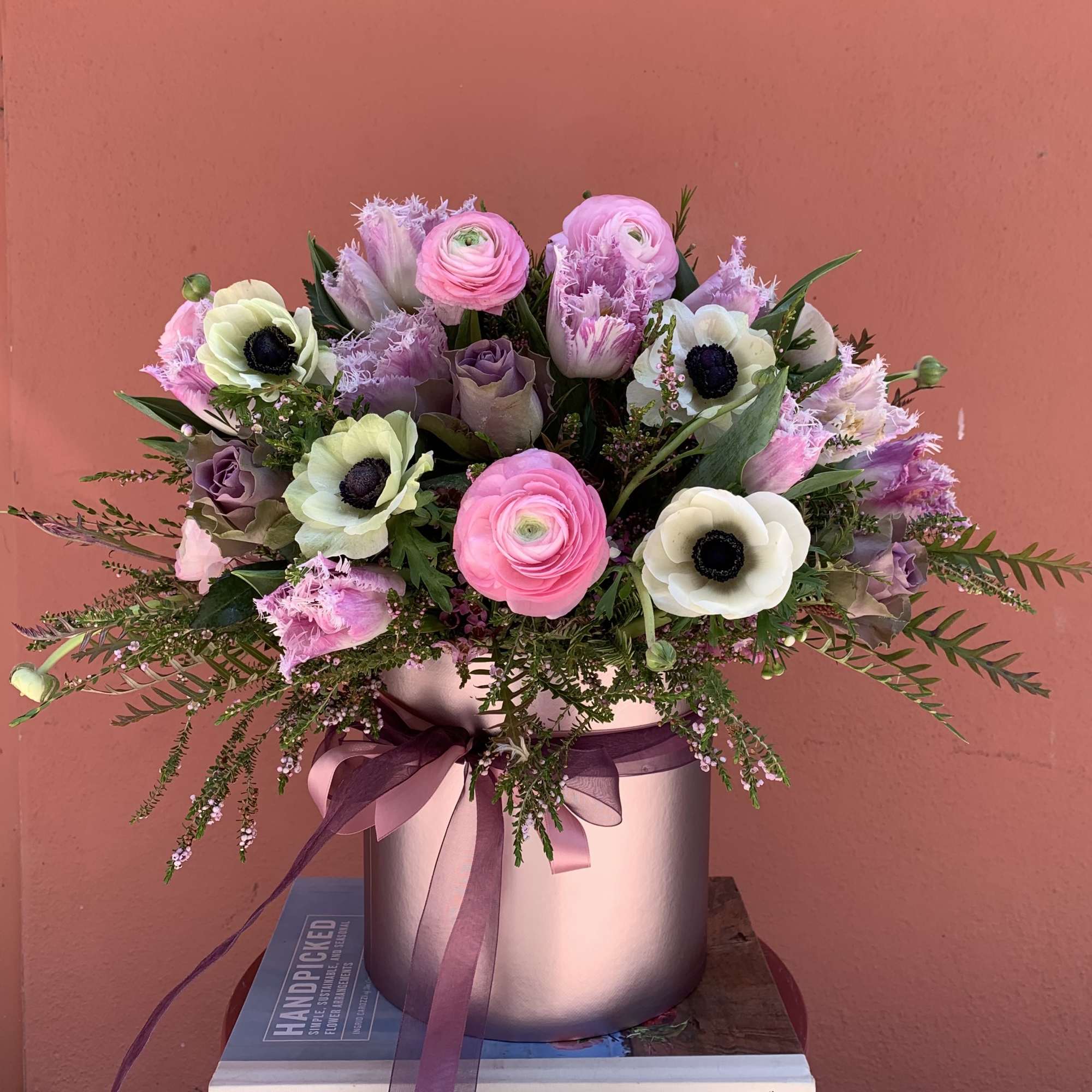 Pink and lavender flower arrangement in a round metallic vase with ribbon