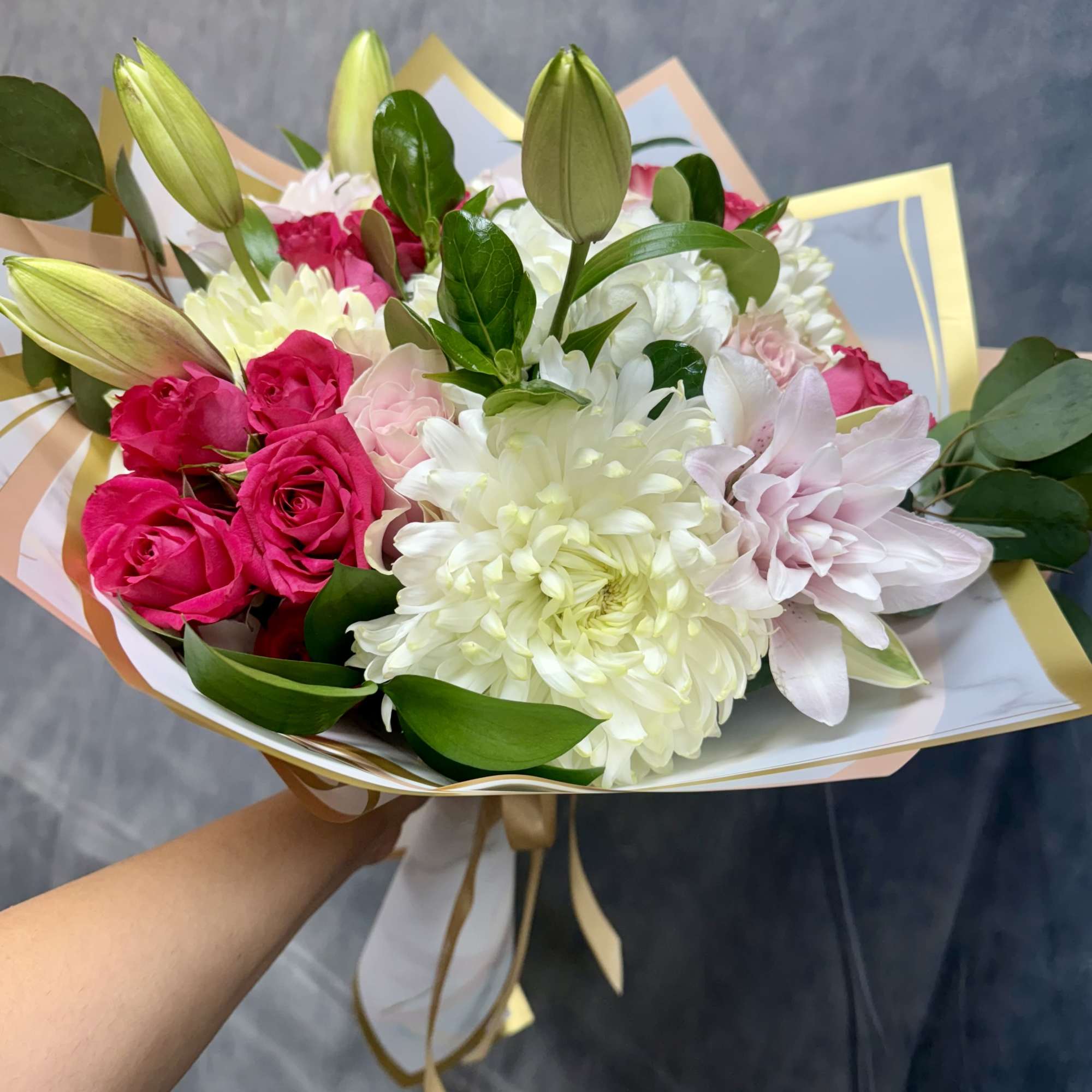 Handheld bouquet of pink roses, white chrysanthemums, and lily buds