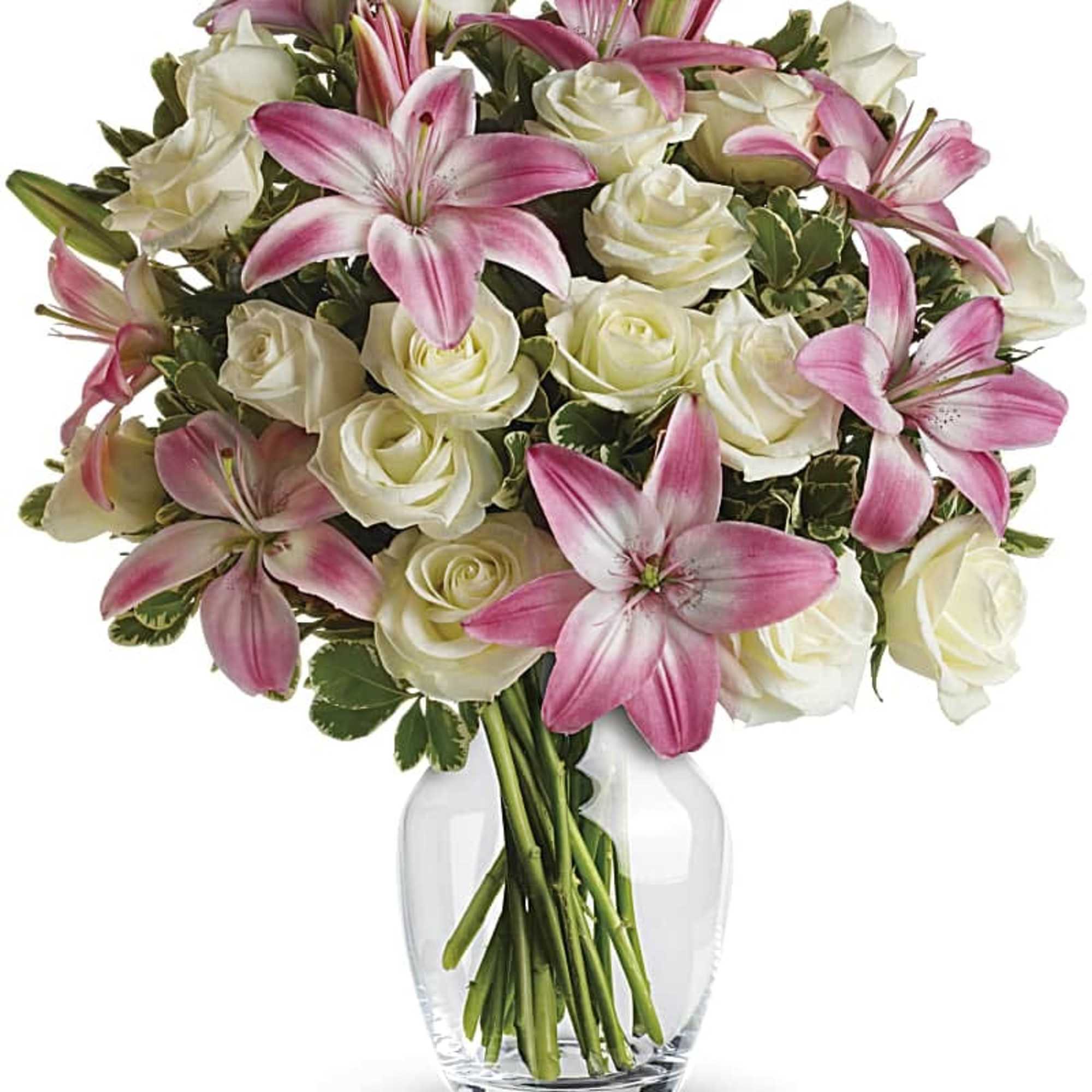 Pink lilies and white roses arranged in a clear glass vase