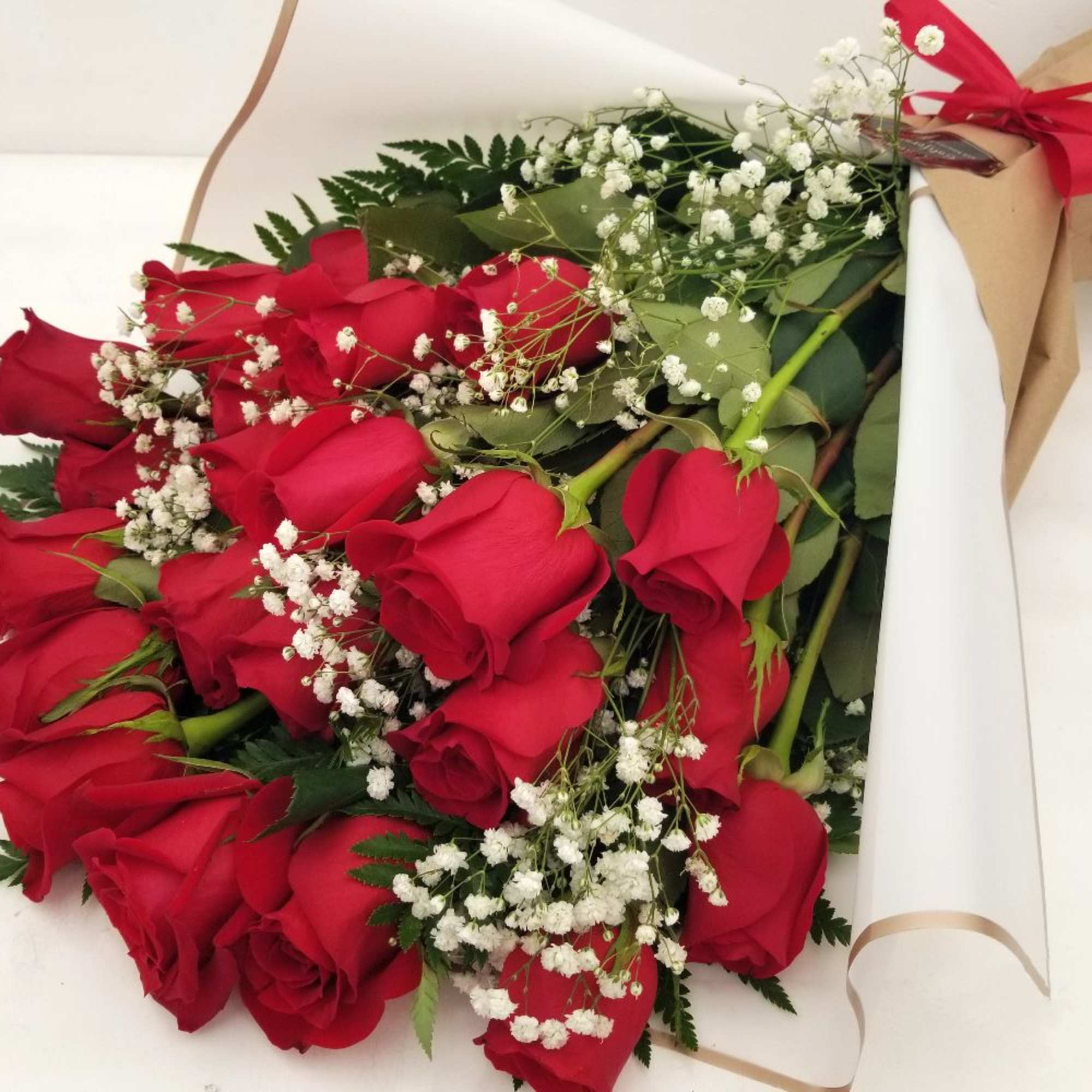 Bouquet of red roses with white baby's breath in brown paper