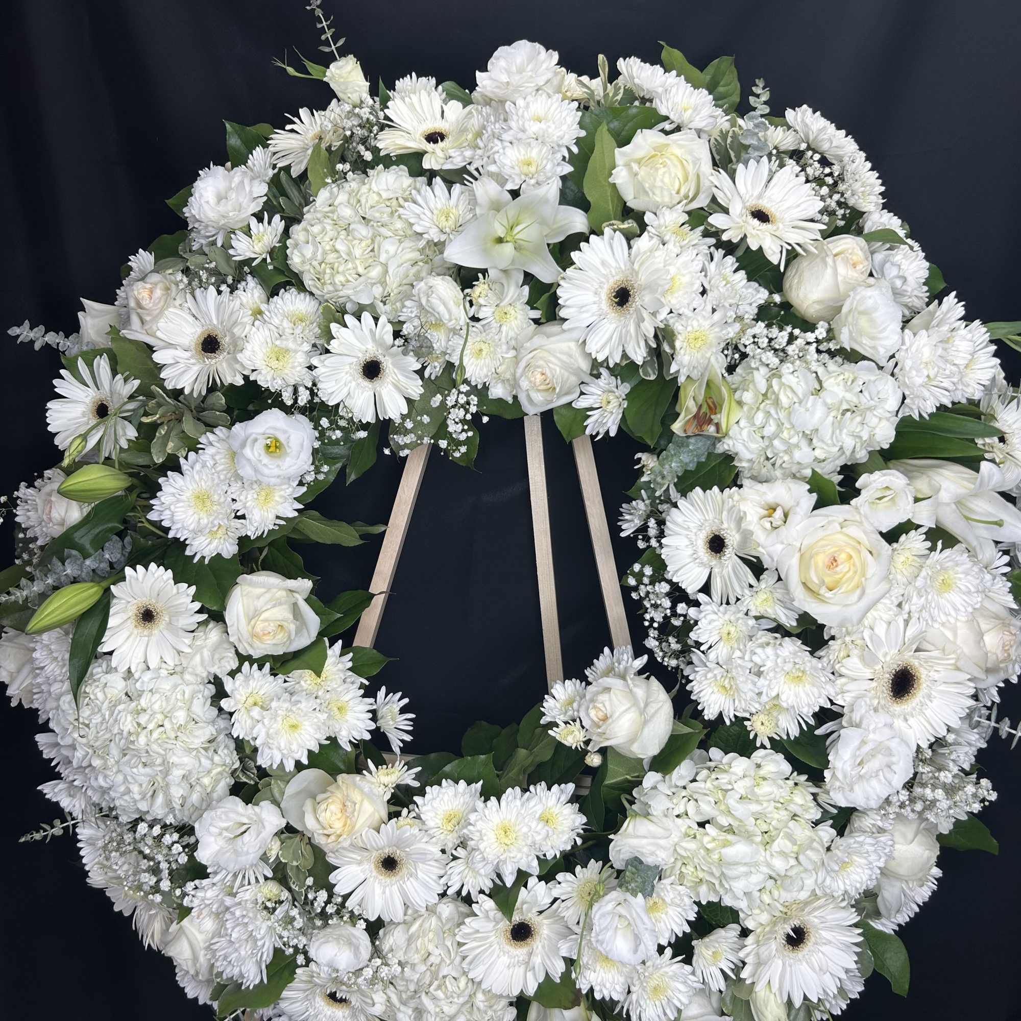 Large white floral wreath on a wooden easel