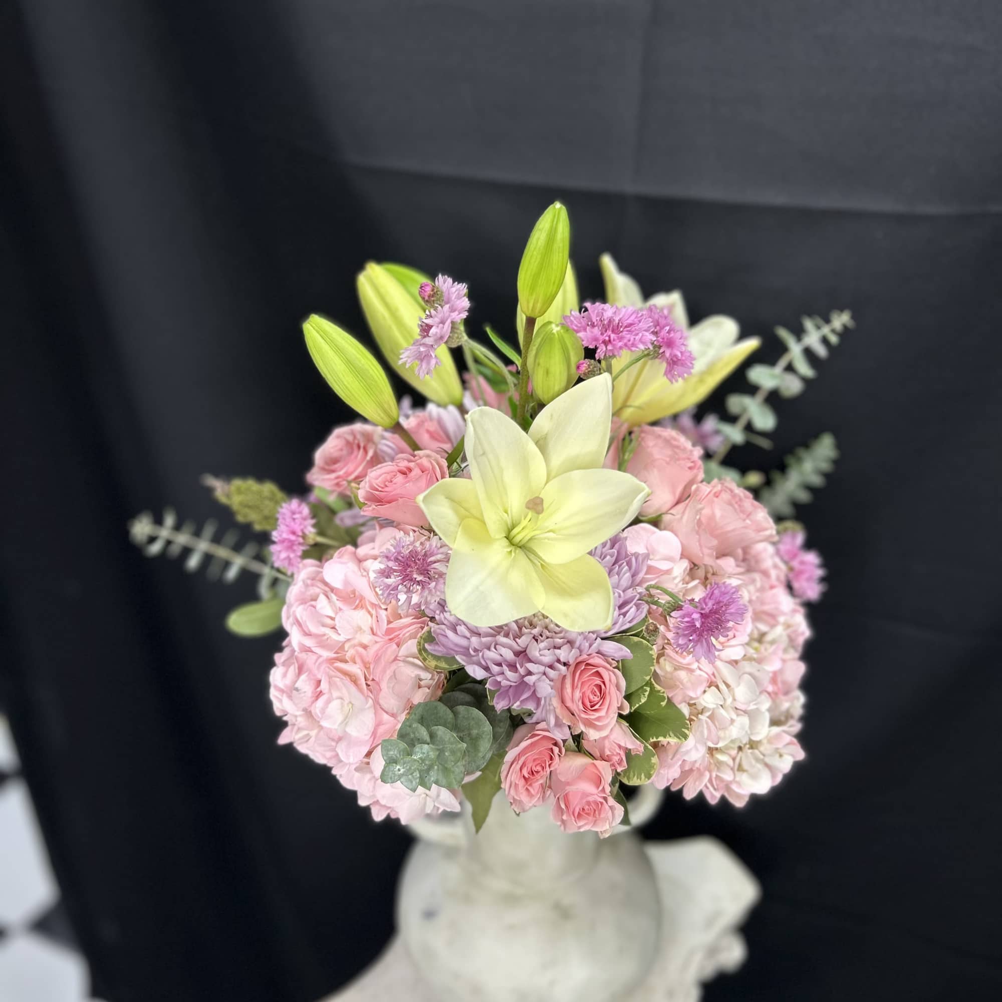 Pink and lavender bouquet with pale yellow lilies in a white vase