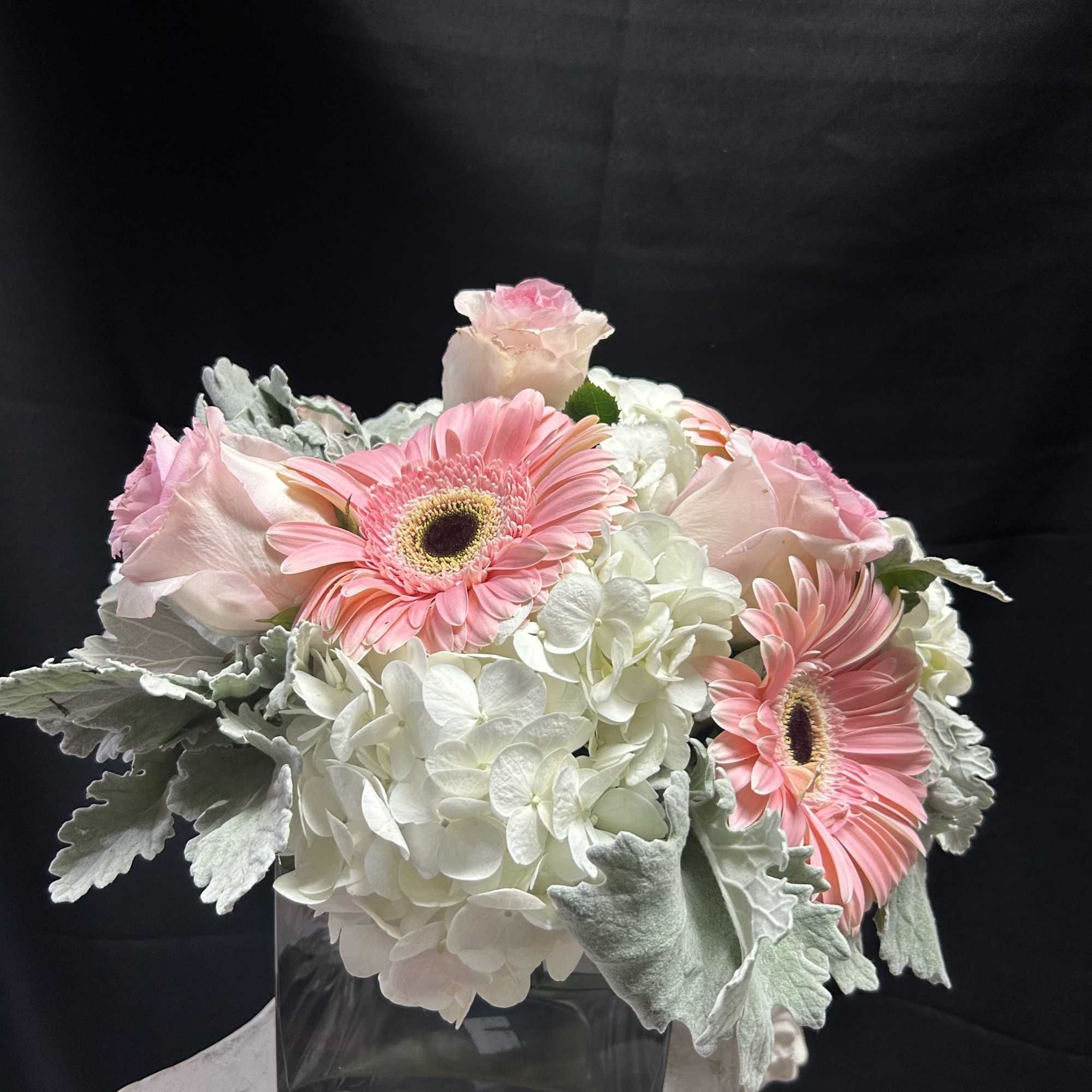 Pink gerbera daisies and pale roses in a square glass vase