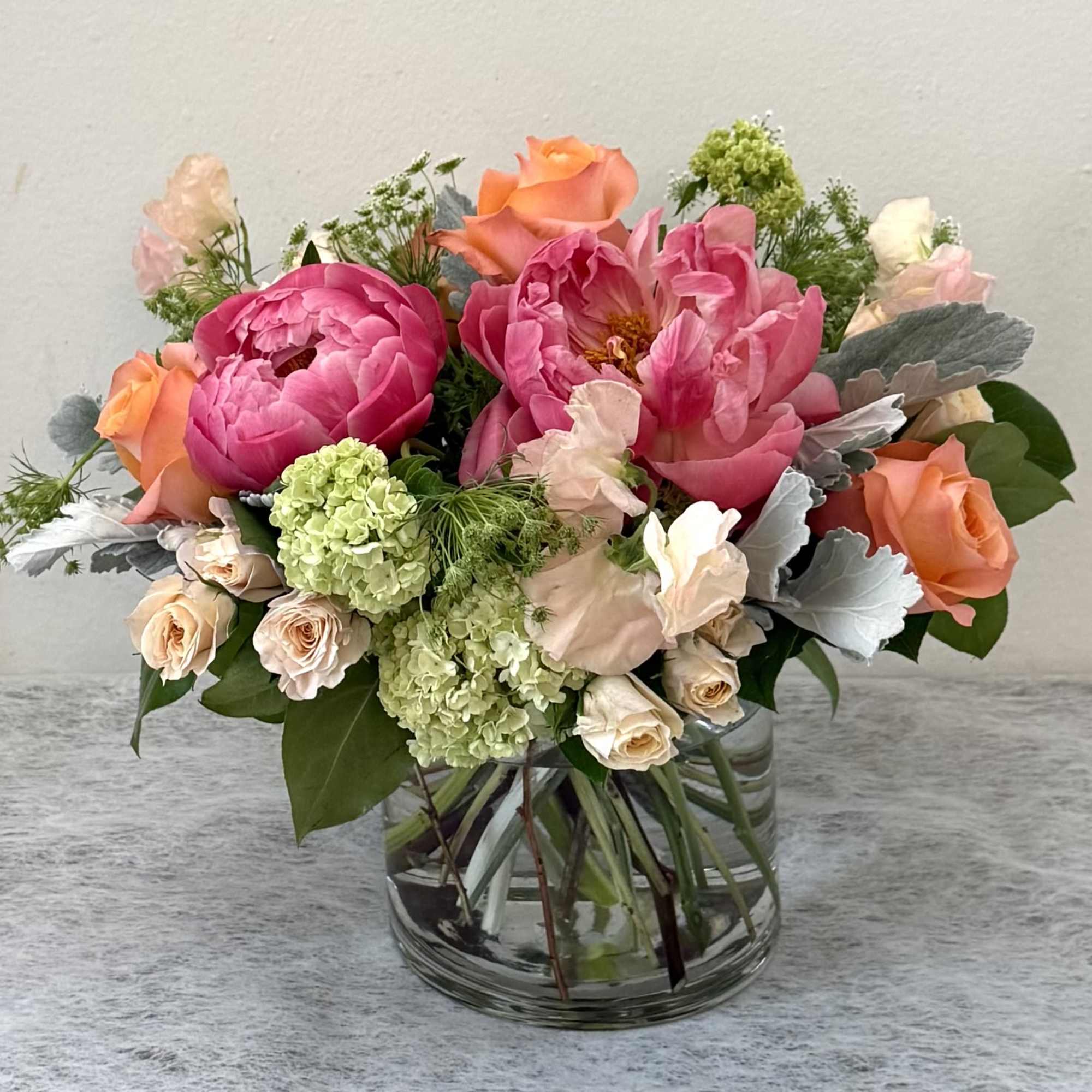 Mixed pink and peach flower arrangement in a clear glass vase