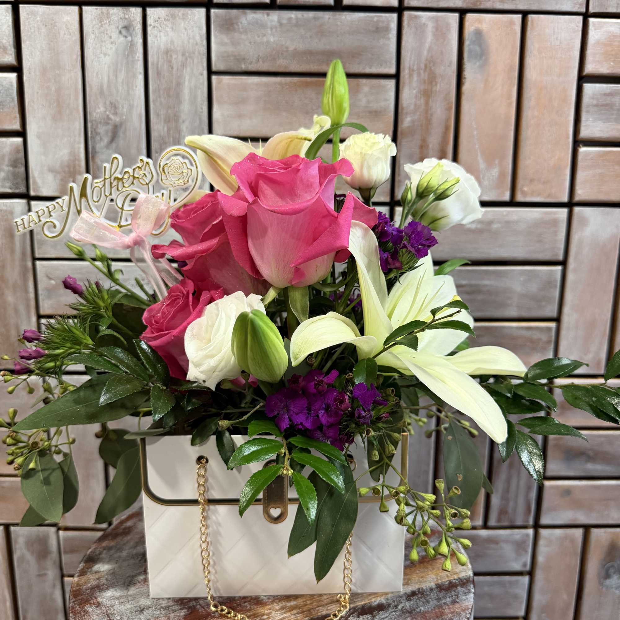 A beautiful purse-inspired floral arrangement featuring vibrant pink roses, creamy white lilies