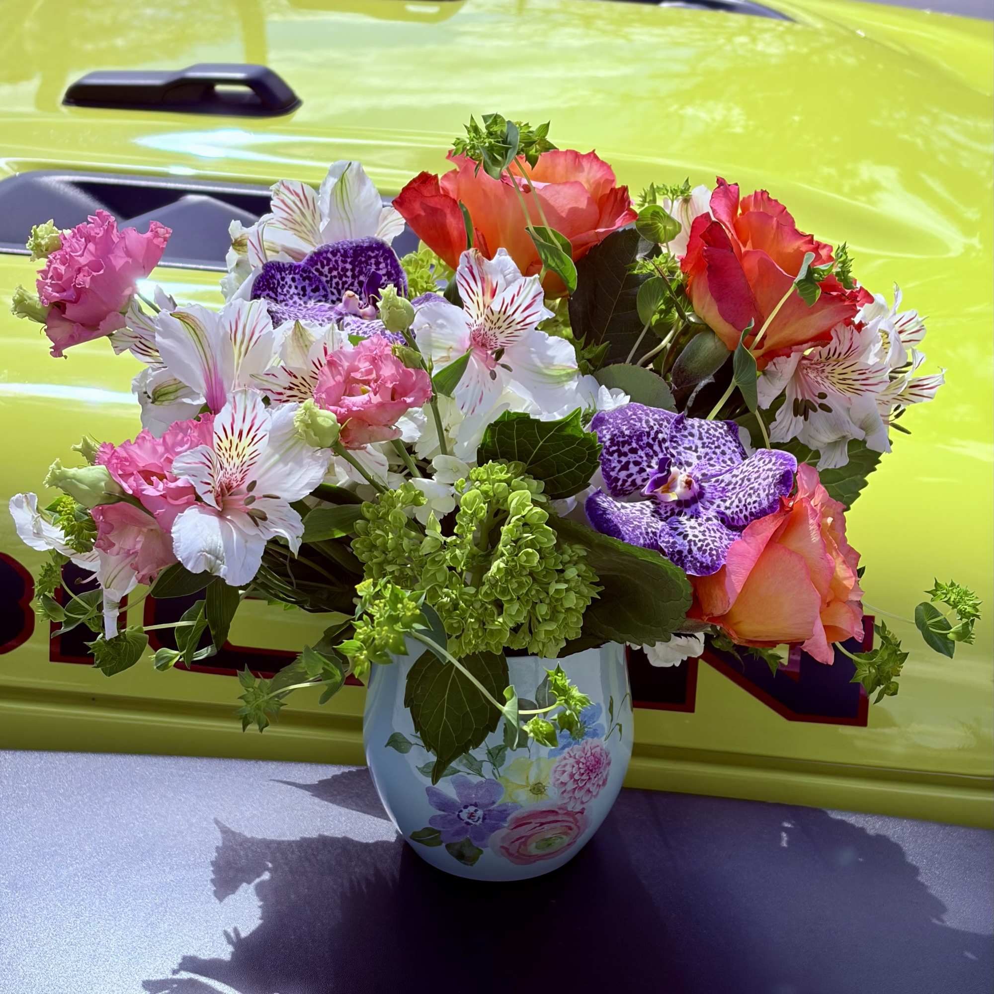 Coral-pink and orange-pink roses take center stage in this Santorini flower arrangement