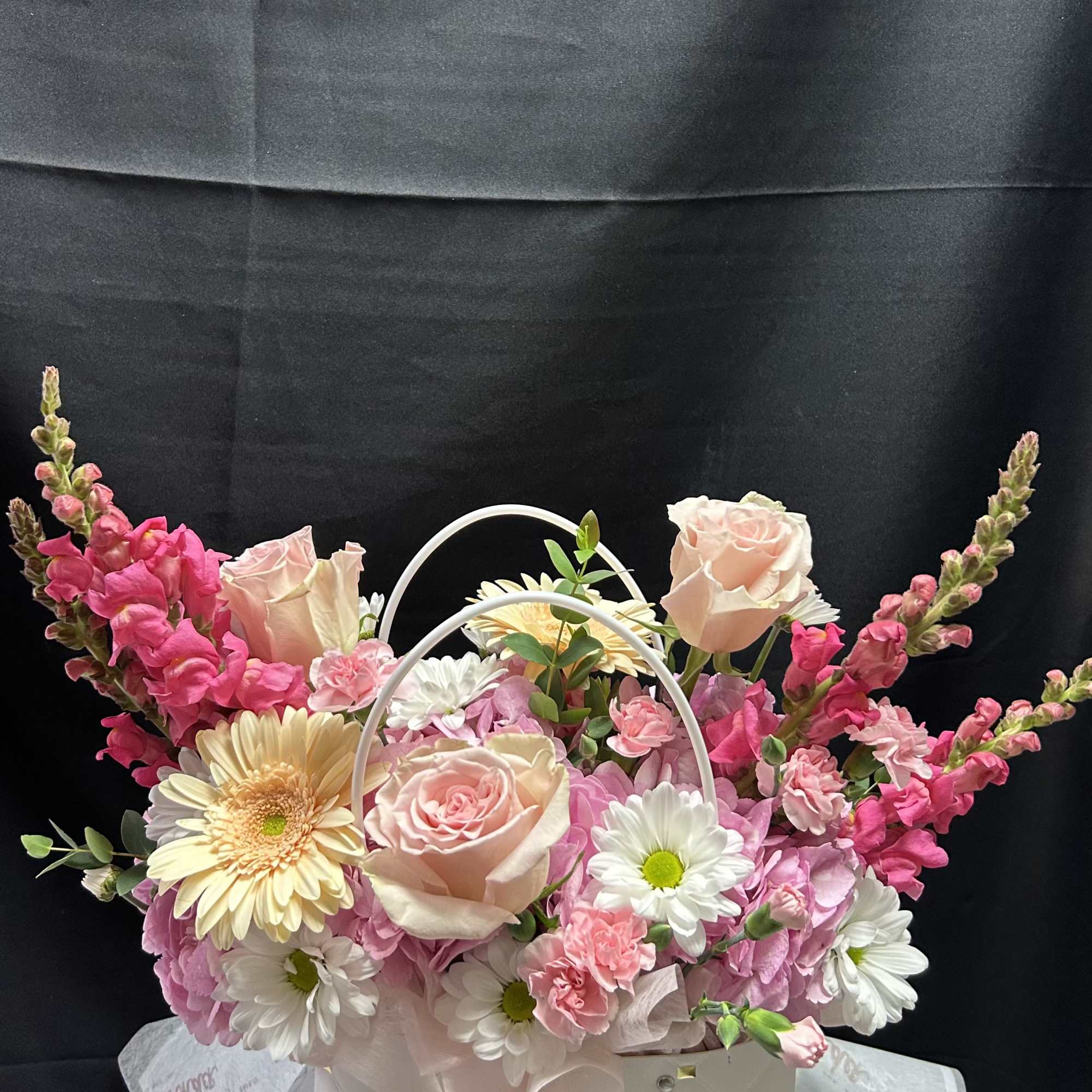 An assortment of small, dainty flowers styled to fit a bag-shaped vase.