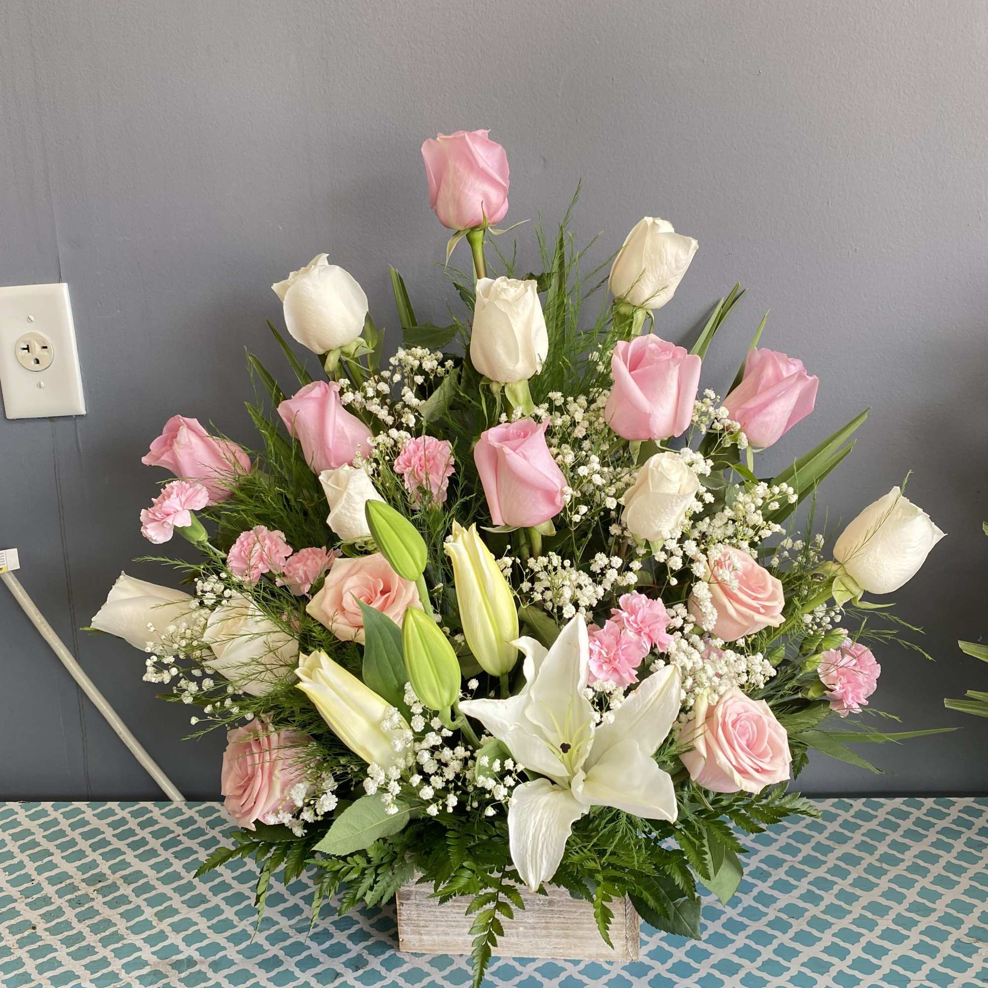 Pink and white roses with lilies in a wooden box arrangement