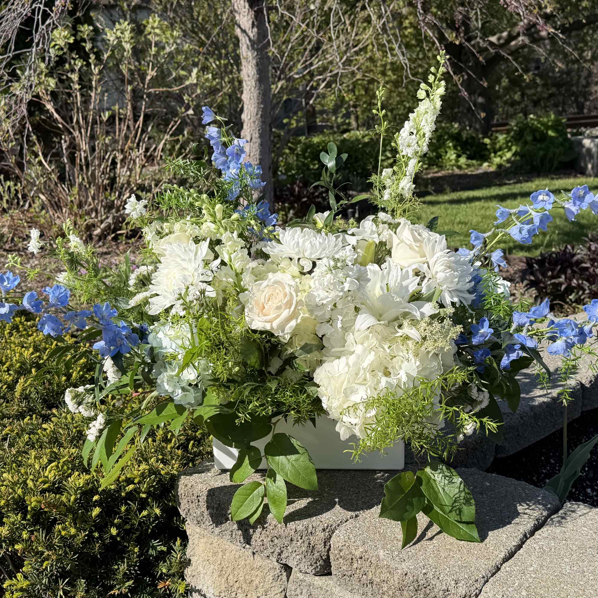 A serene cluster of white roses, hydrangeas and chrysanthemums framed by tall