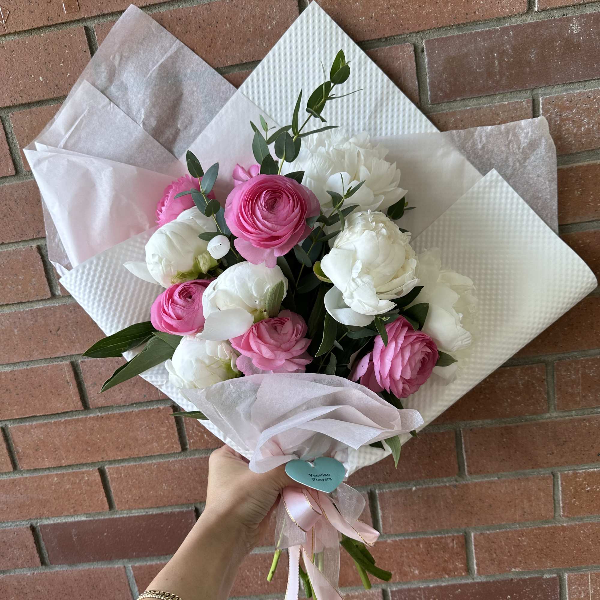 Pink and white flower bouquet wrapped in pale paper with a ribbon