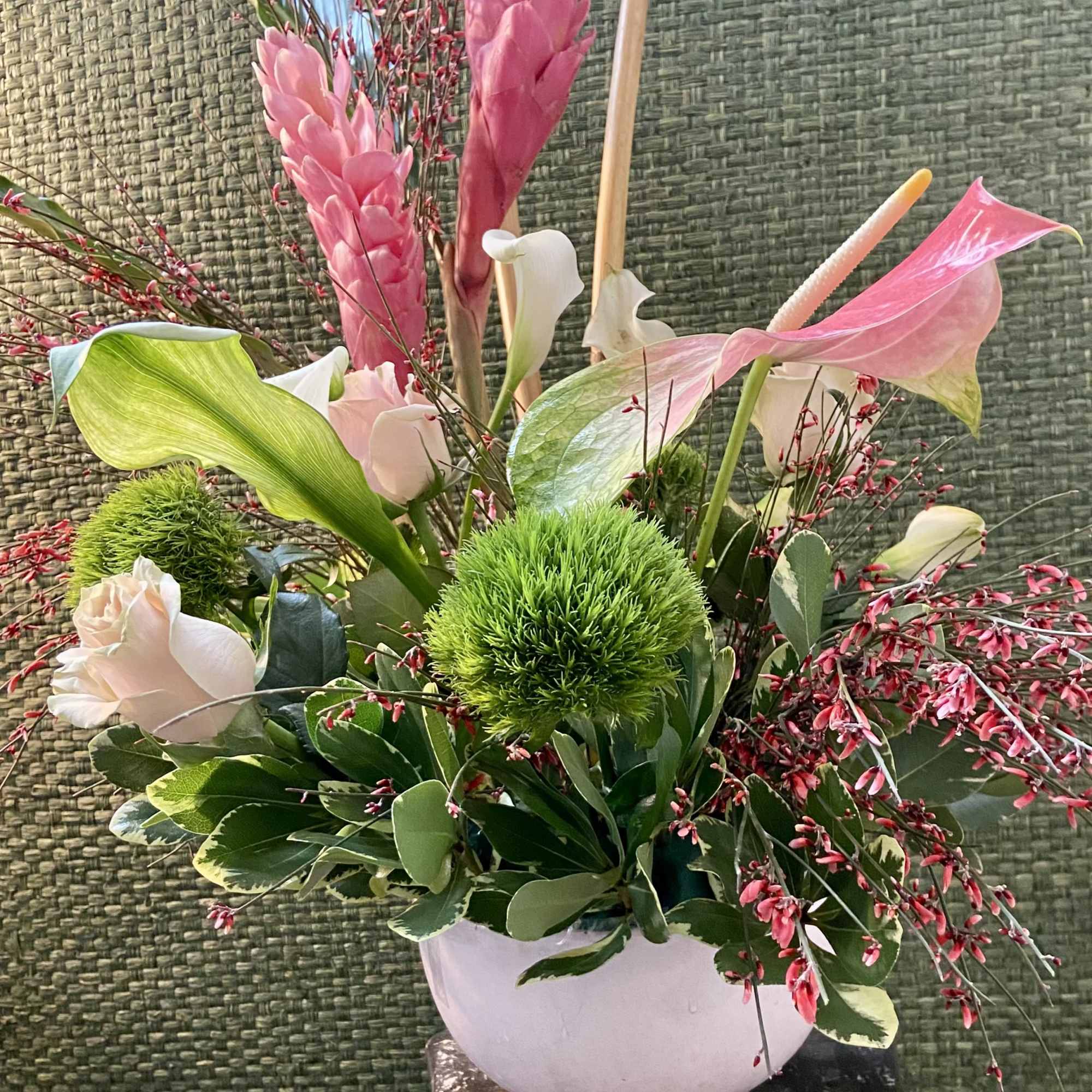 Pink and white floral arrangement in a white vase with green accents