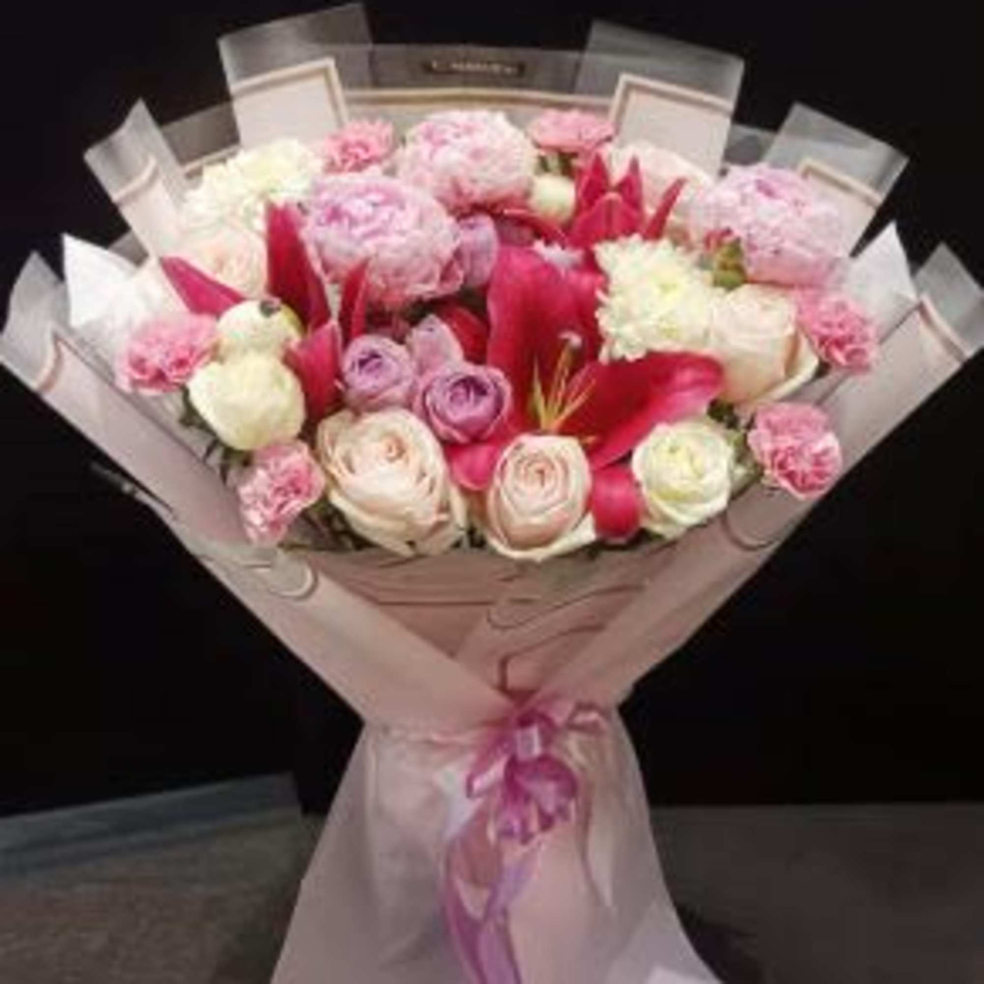 Pink and white bouquet with roses and lilies wrapped in pale paper