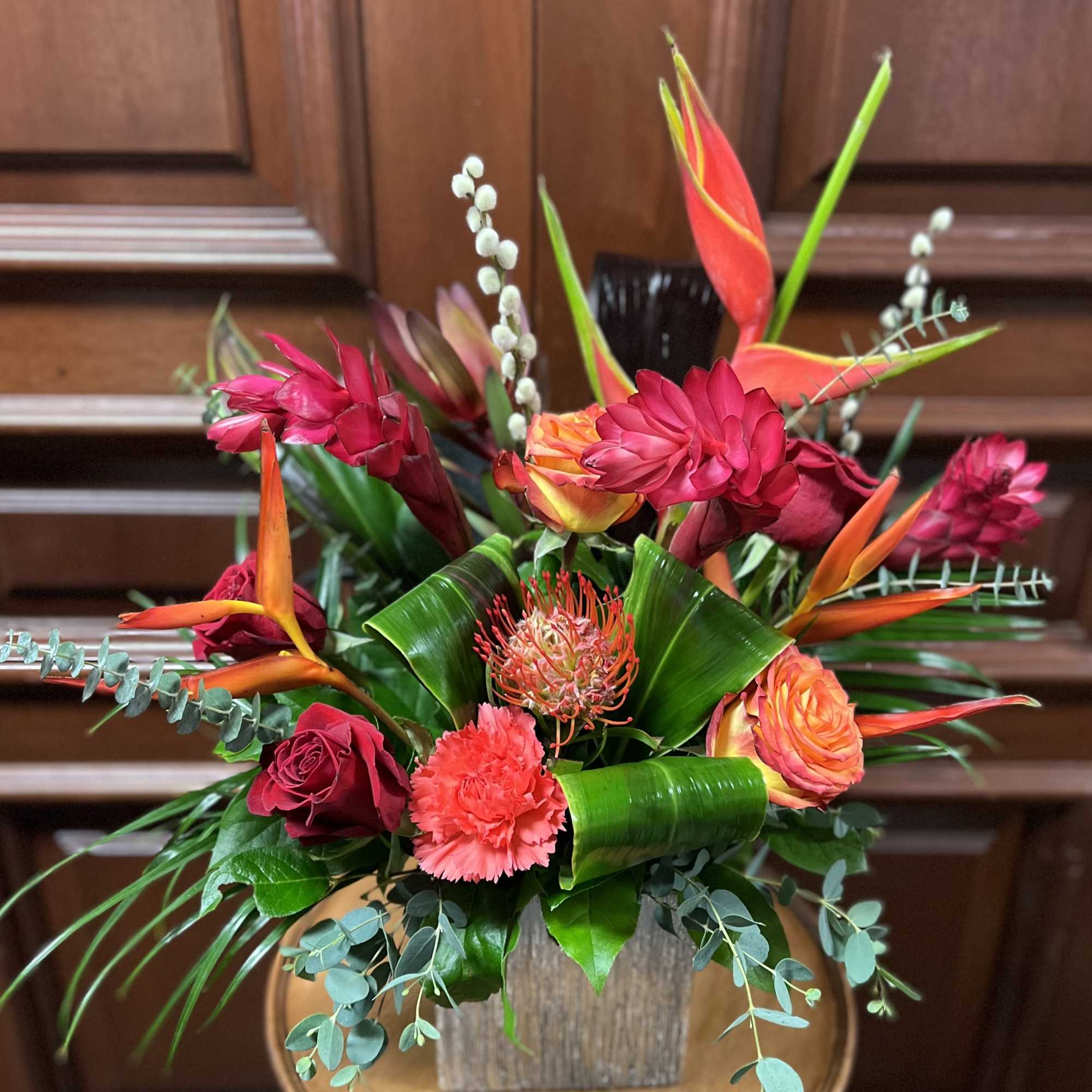 Tropical bouquet with red and orange flowers in a wooden container