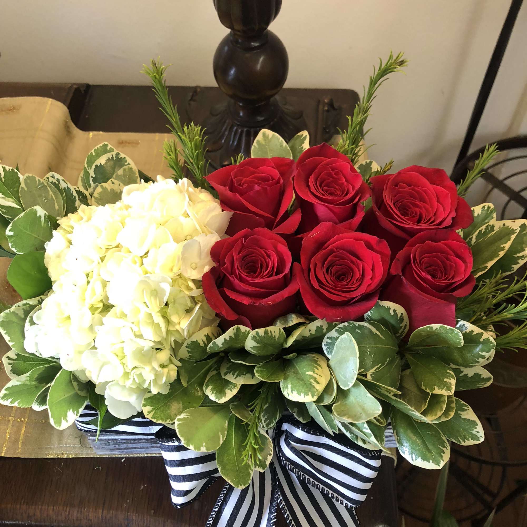 Red roses and white hydrangeas in a striped ribbon-wrapped arrangement