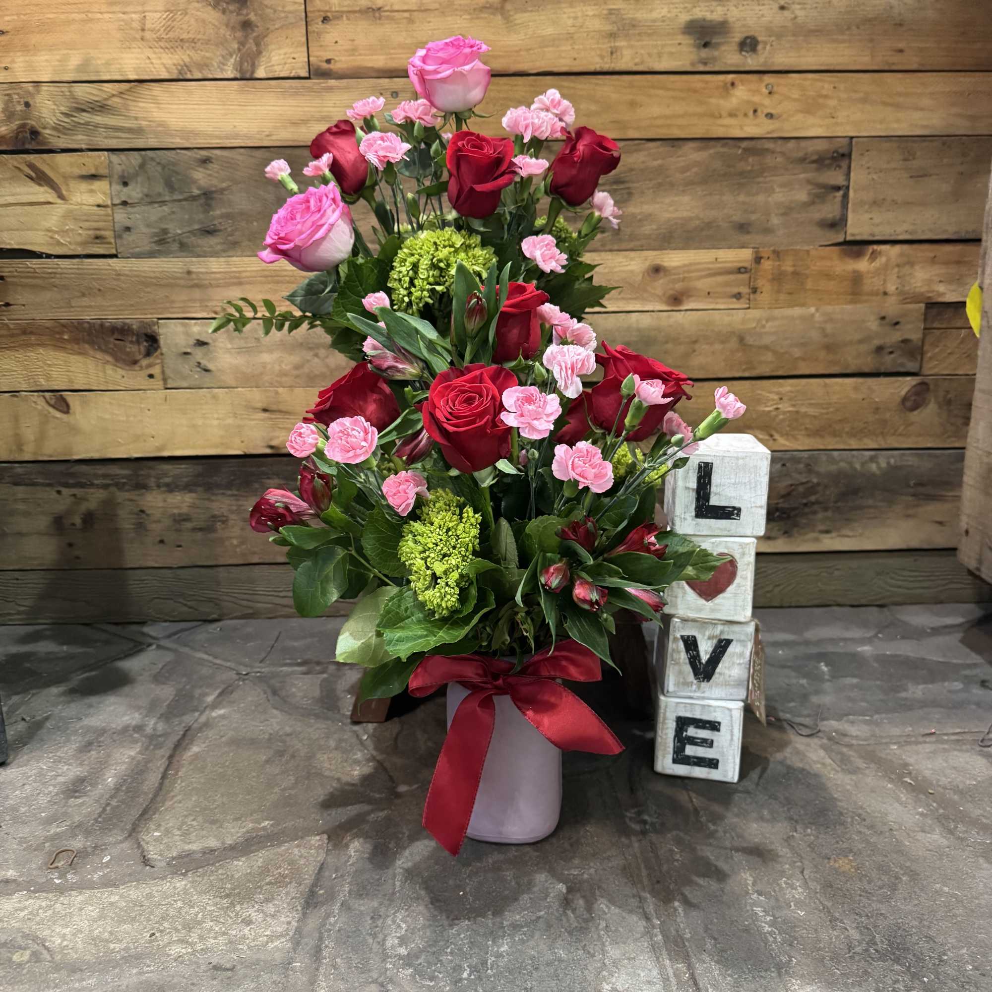 Pink and red rose arrangement in a vase with a ribbon
