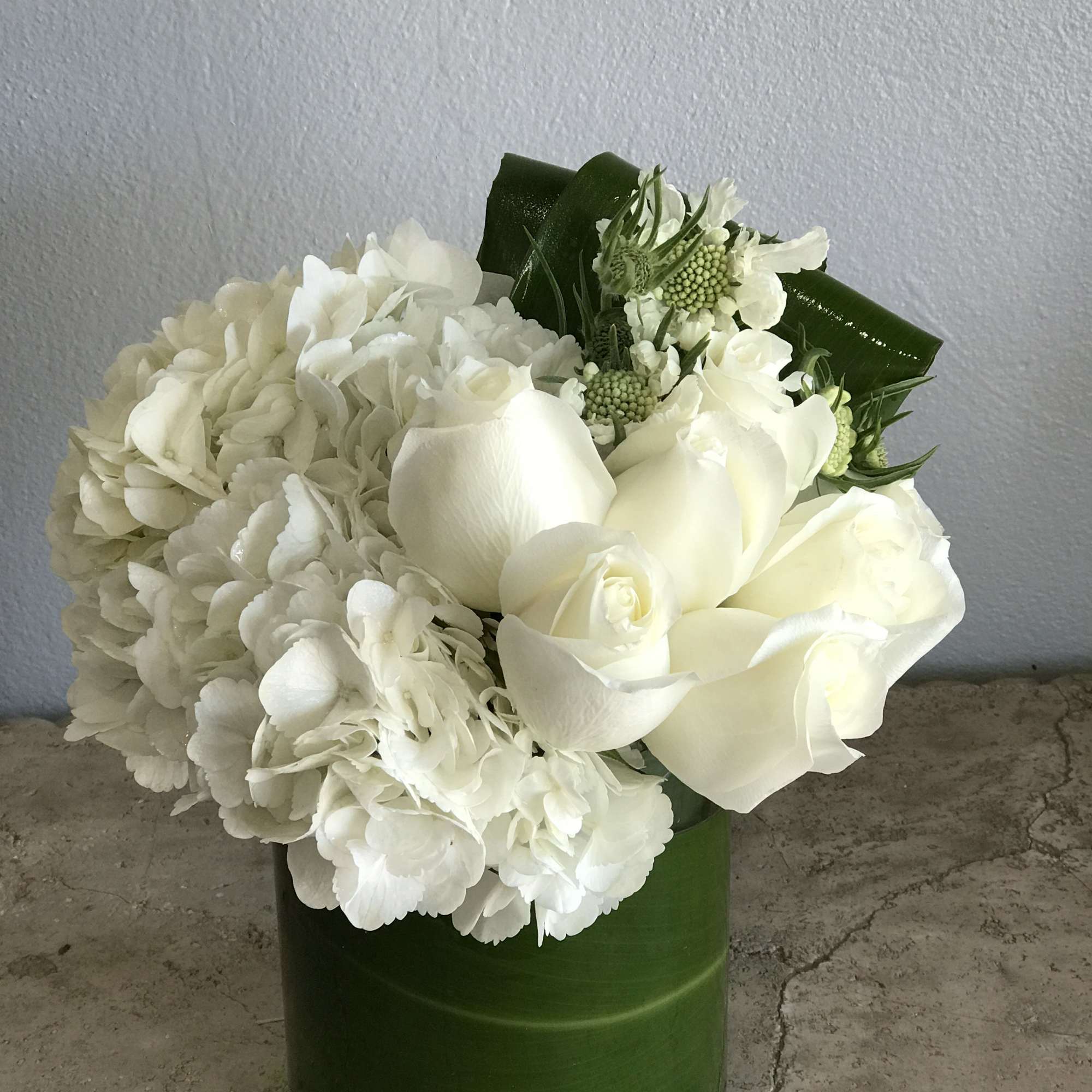 White floral arrangement in a green cylindrical vase