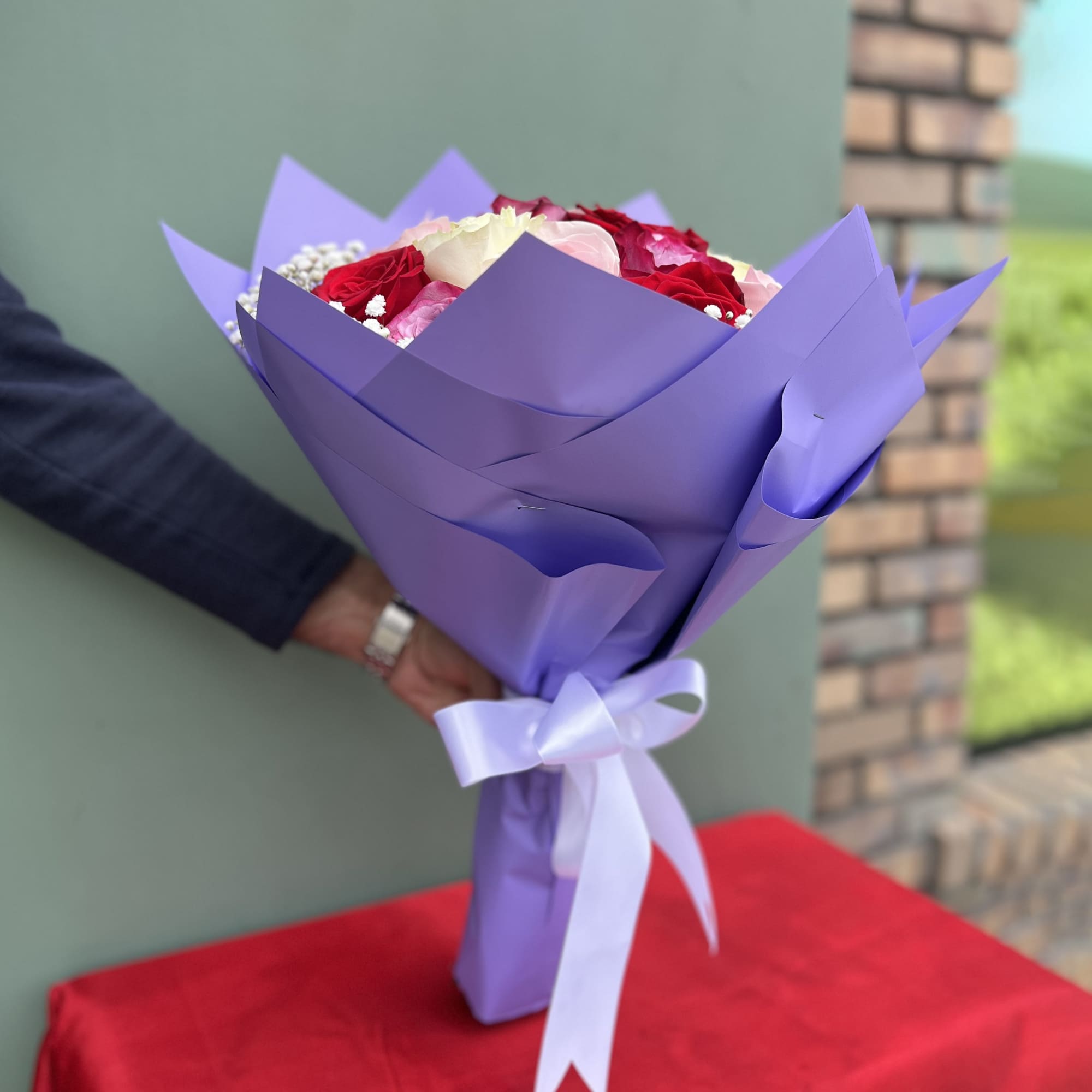 This bouquet features a beautiful mix of red, pink, and cream roses