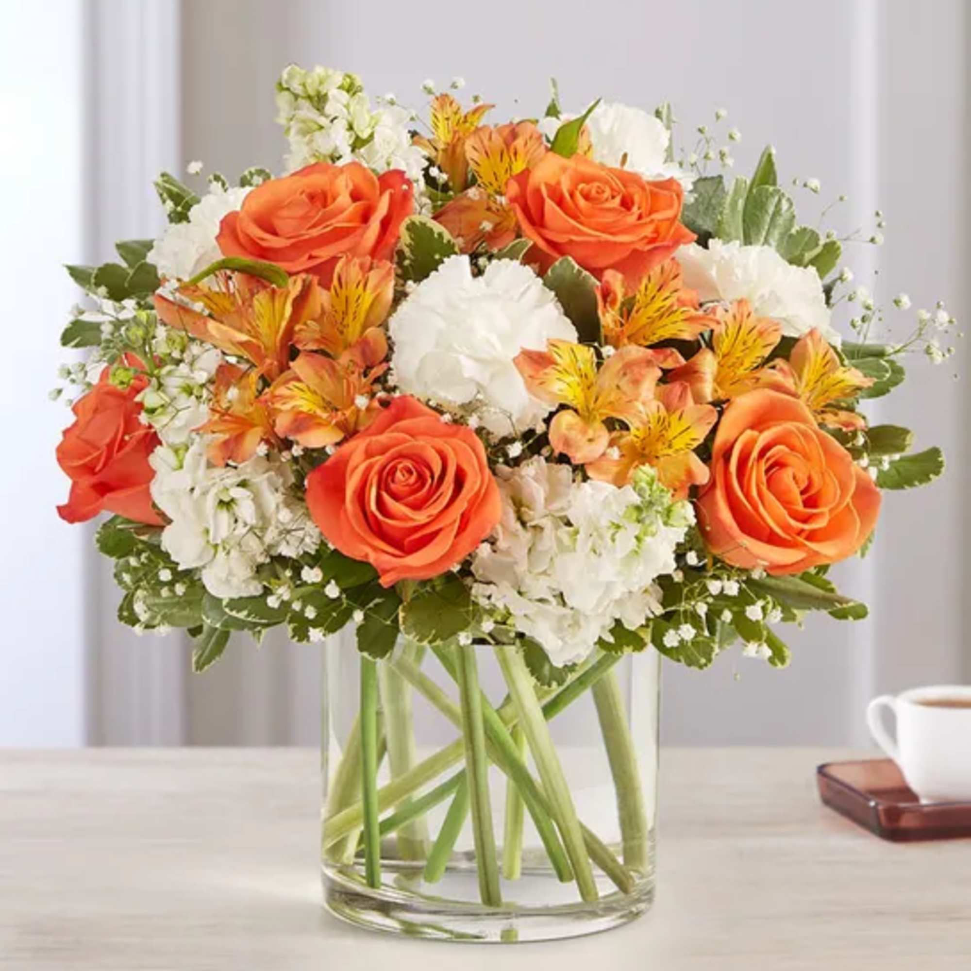 Orange roses and white flowers in a clear glass vase
