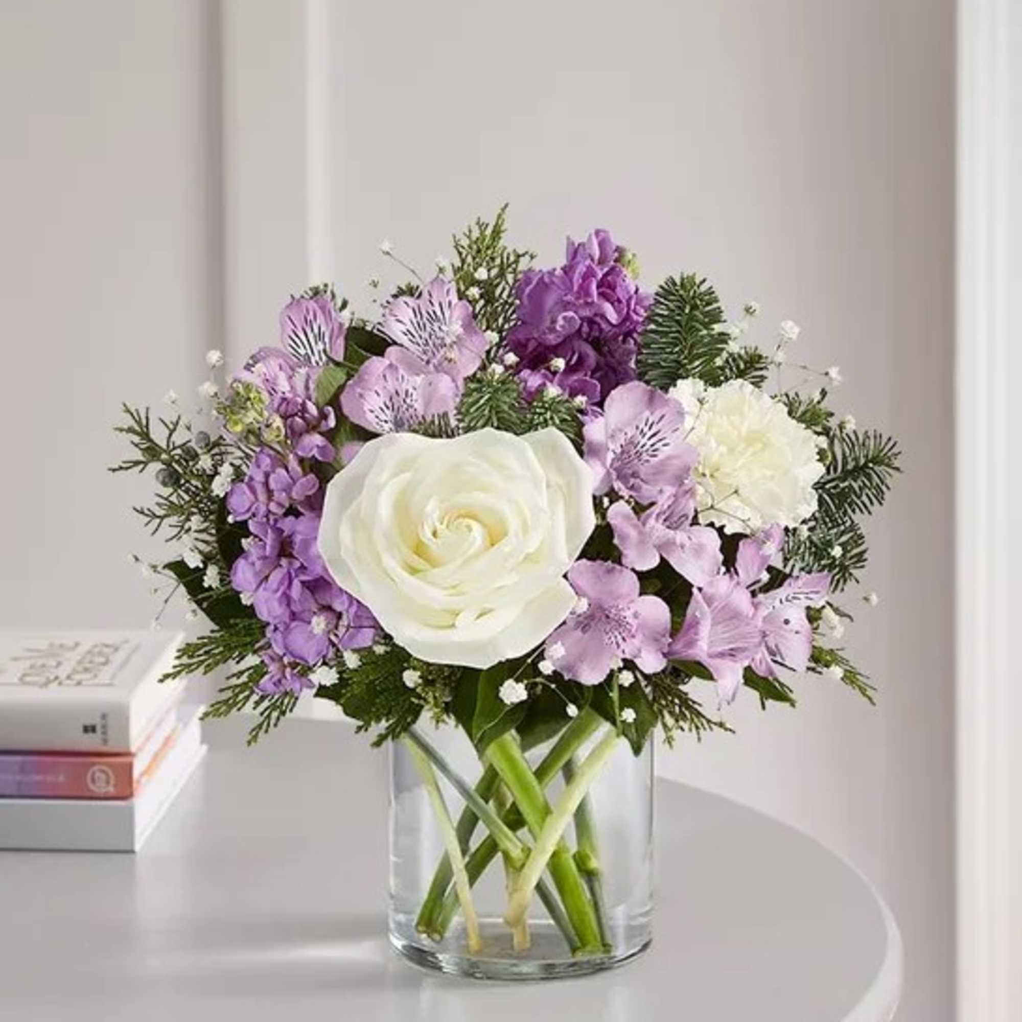 White rose and purple flower bouquet in a clear glass vase