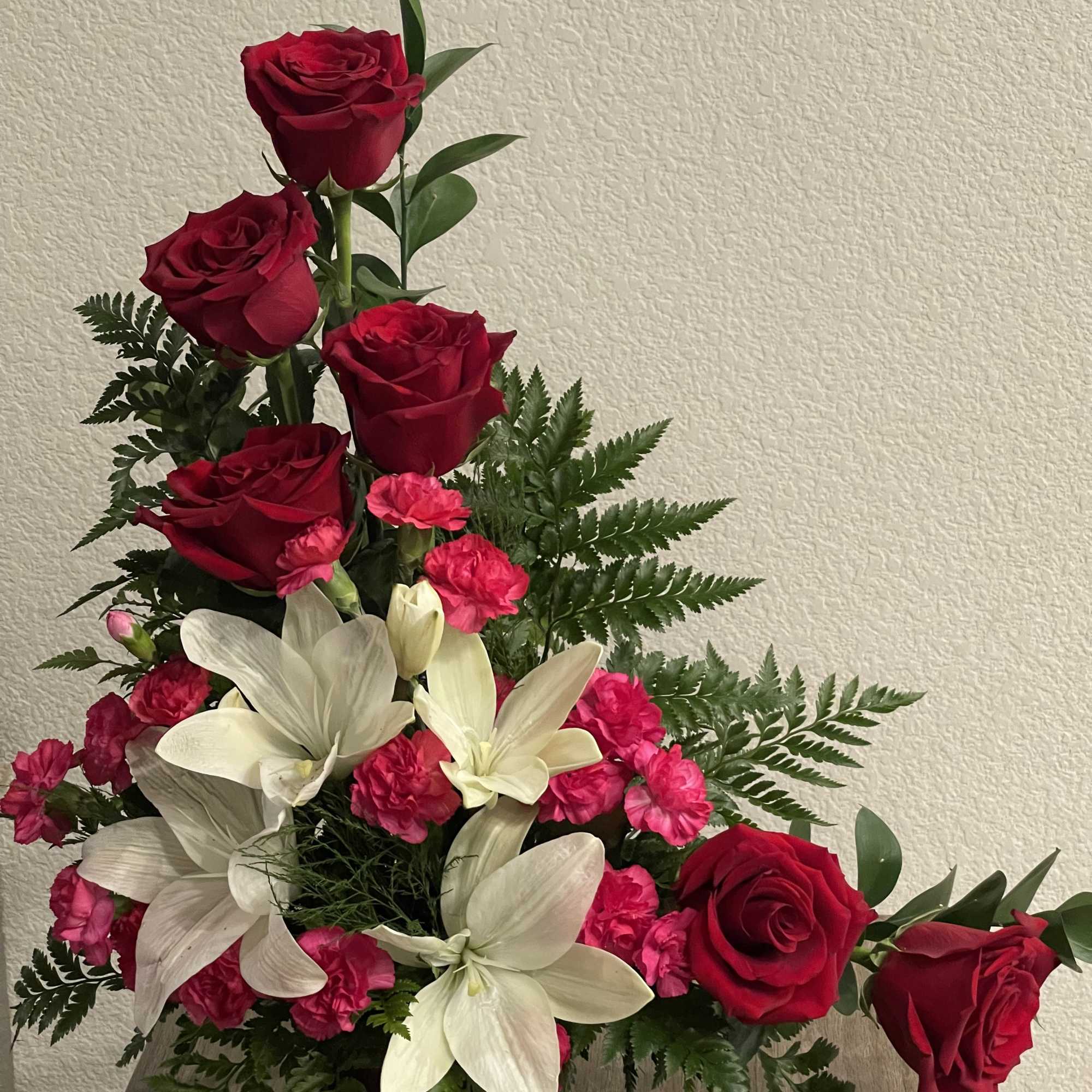 Tall red roses lift the eye above clusters of large white lilies