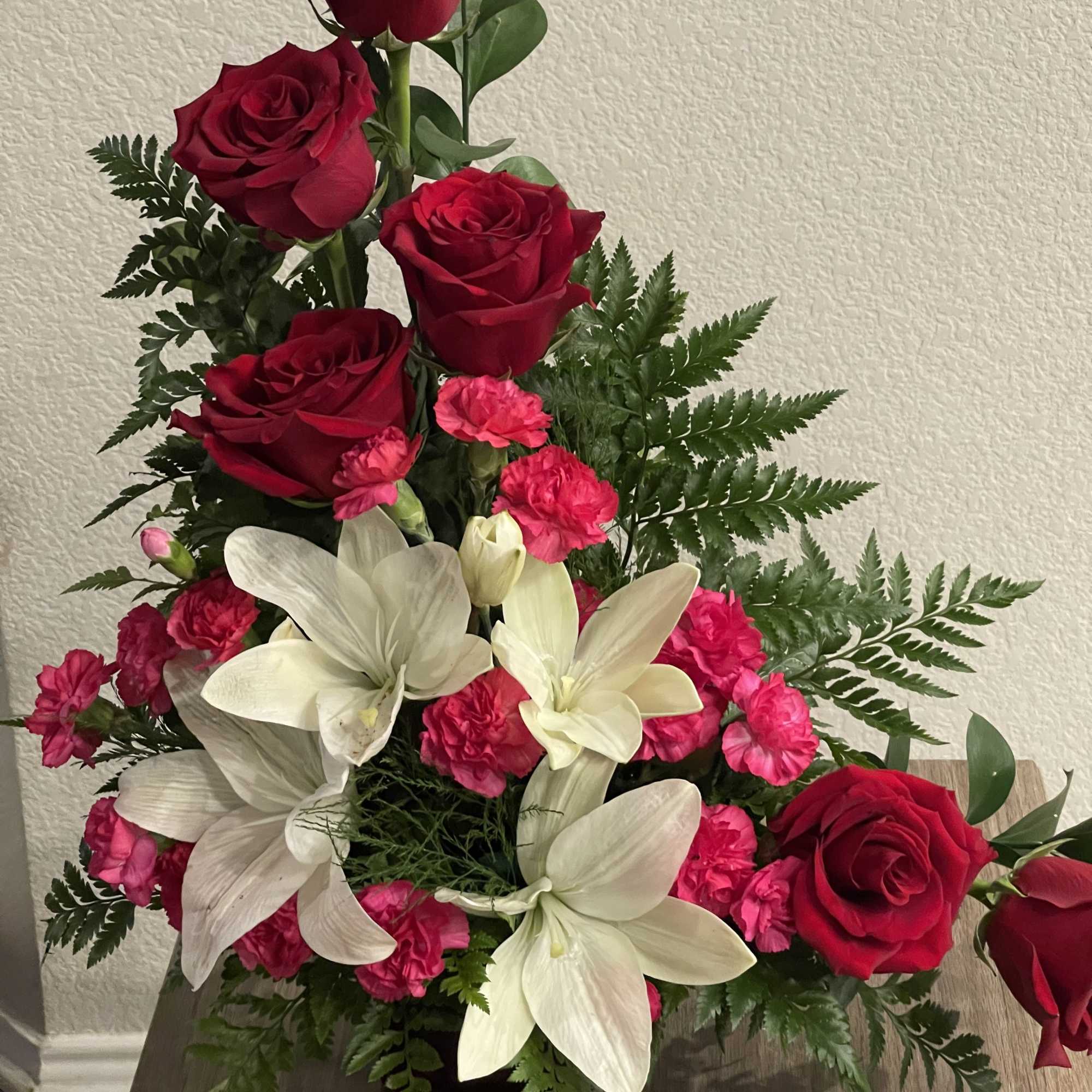 Tall red roses lift the eye above clusters of large white lilies