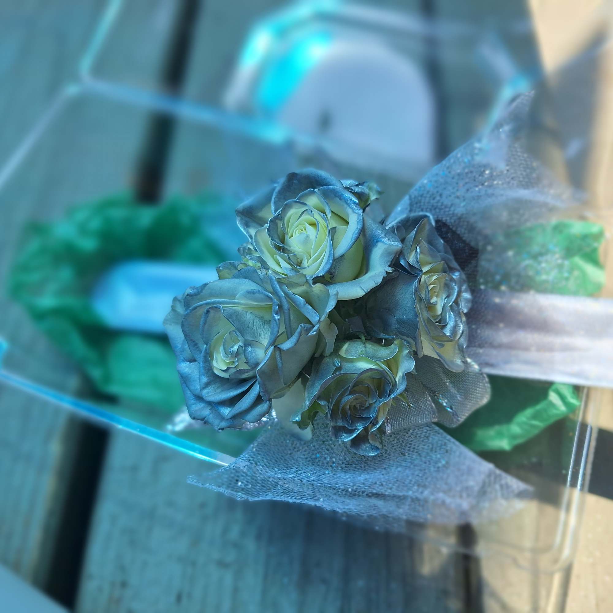 Small bouquet of blue-tinted roses wrapped in sheer mesh