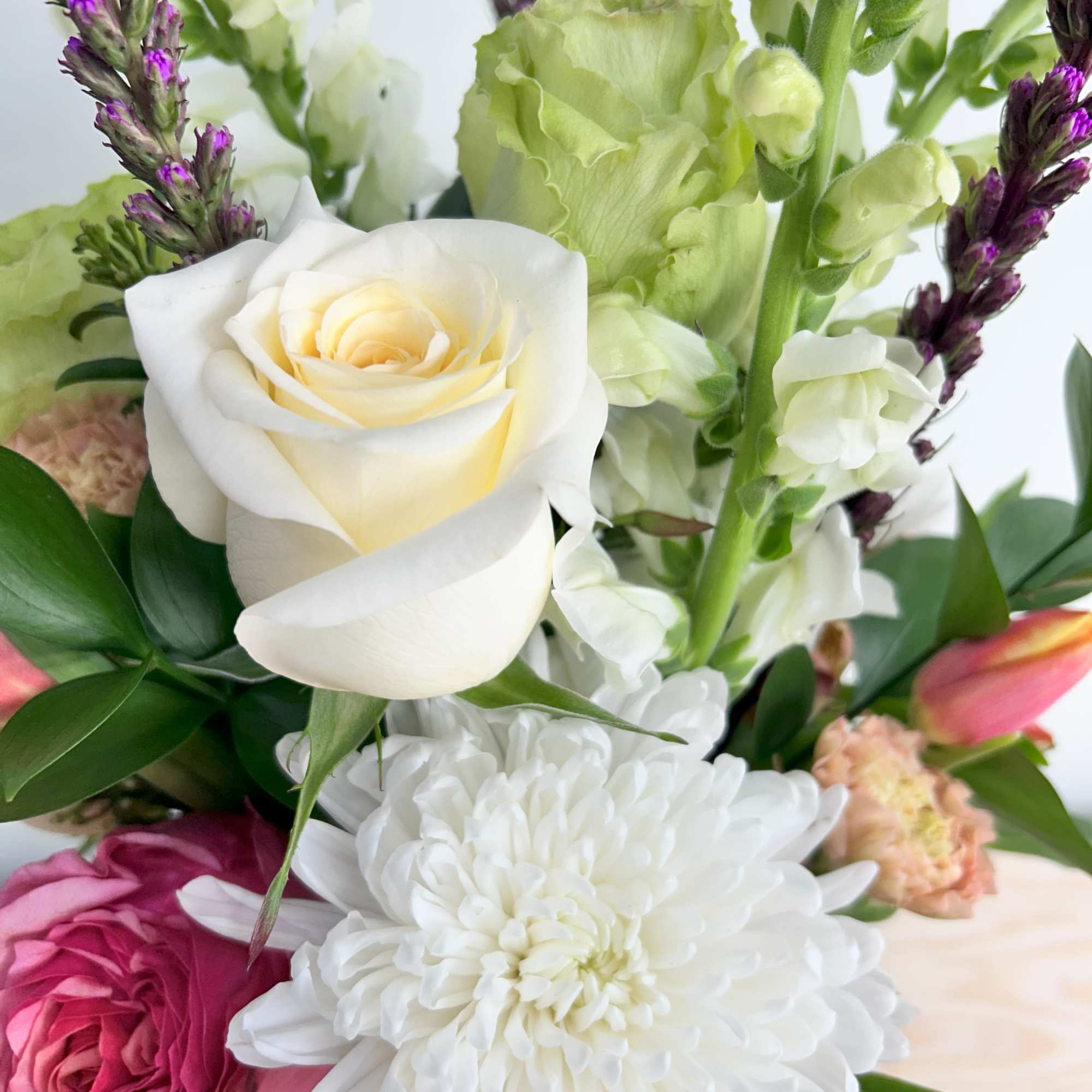 Mixed bouquet with white rose, large white mum, pink rose, snapdragons, carnations, and purple accent spikes