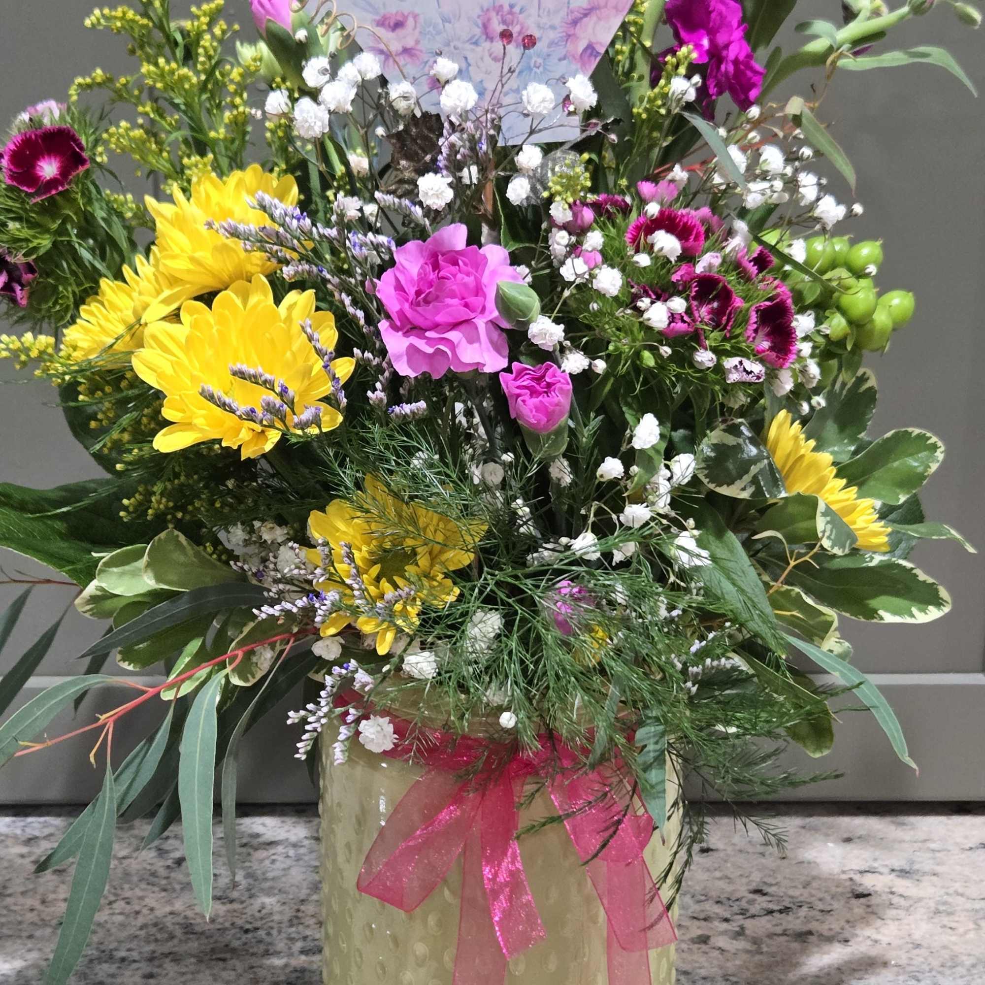 Sunshine-bright yellow chrysanthemums and hot pink carnations give this mixed flower arrangement