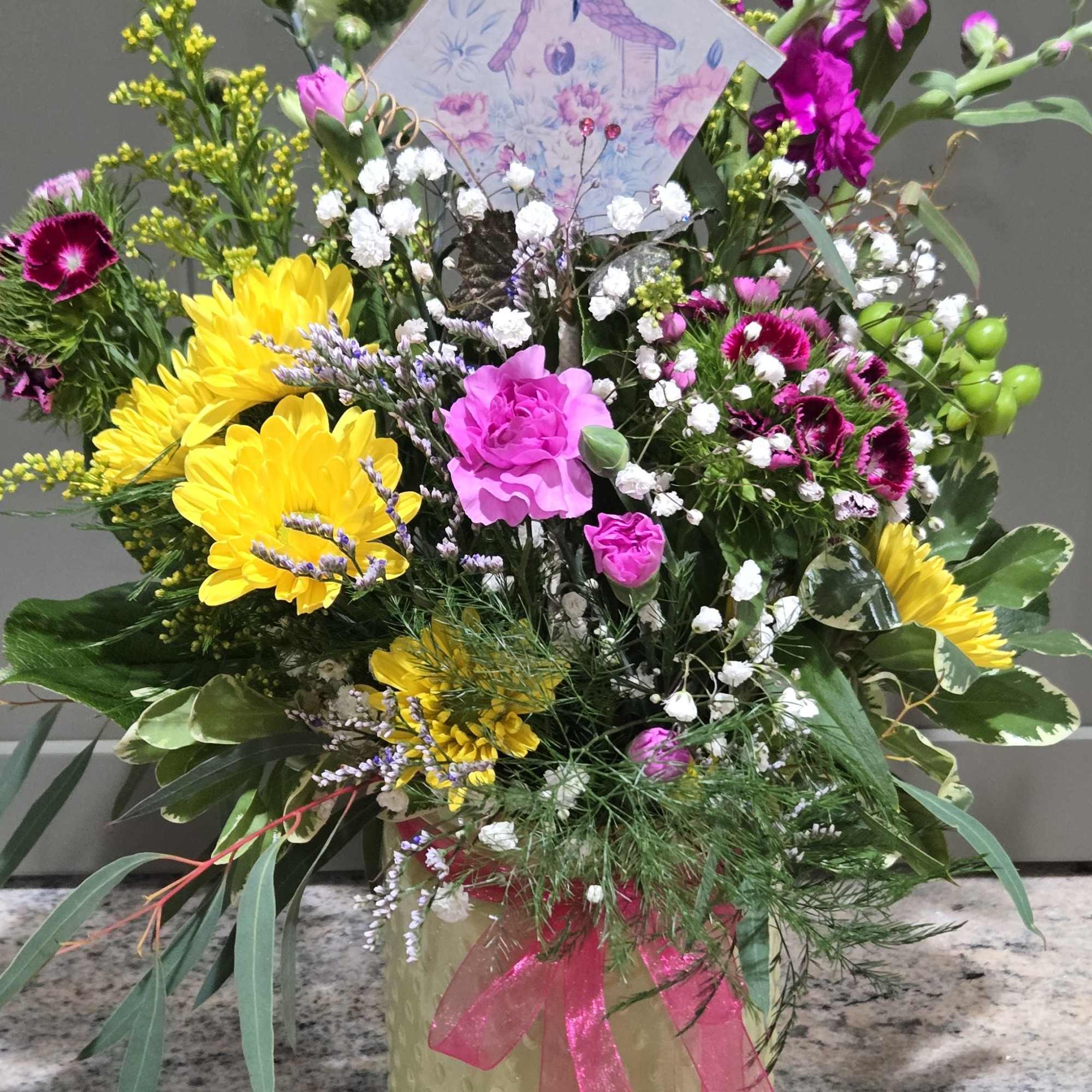 Sunshine-bright yellow chrysanthemums and hot pink carnations give this mixed flower arrangement
