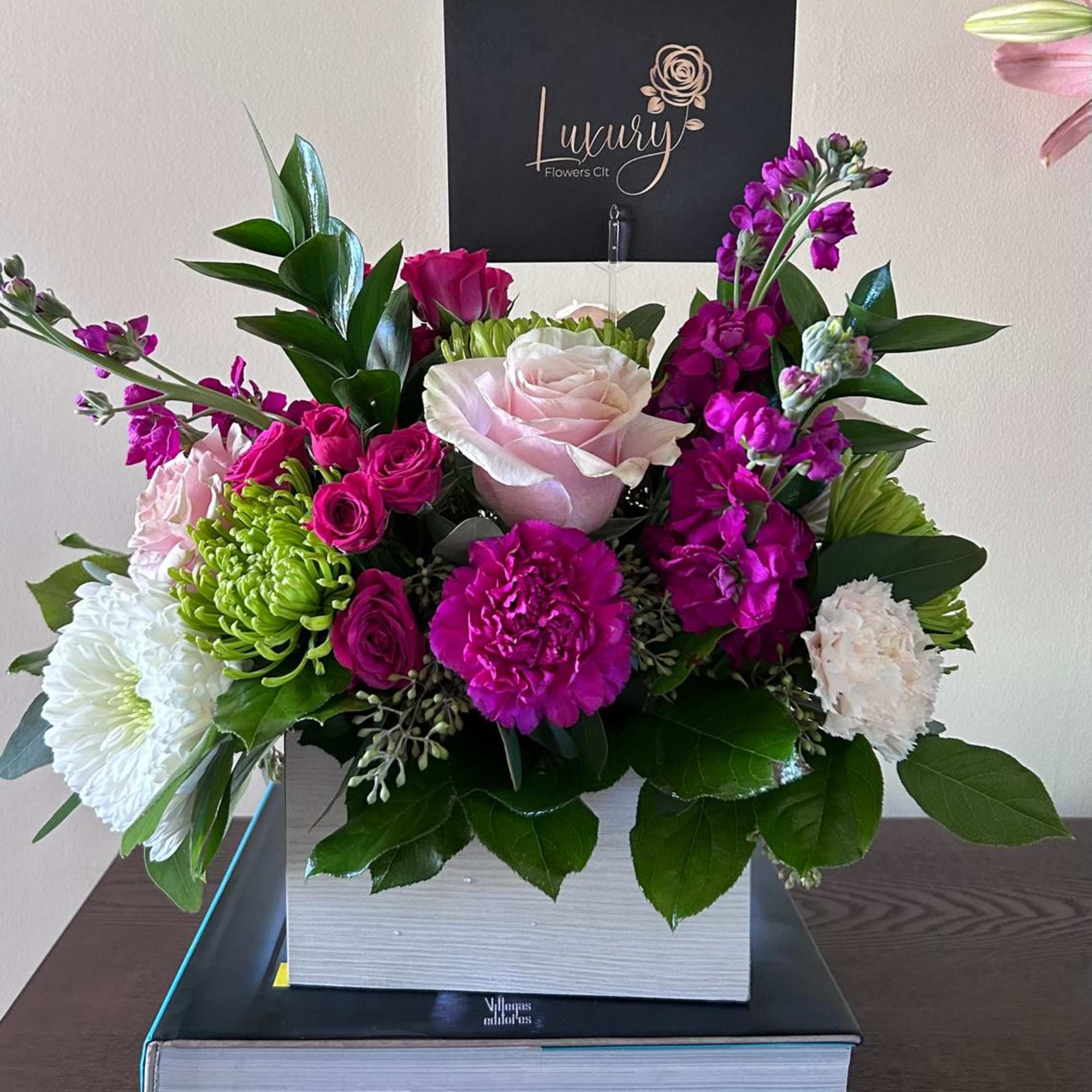 Mixed bouquet with pink roses, white blooms, and purple flowers in a box