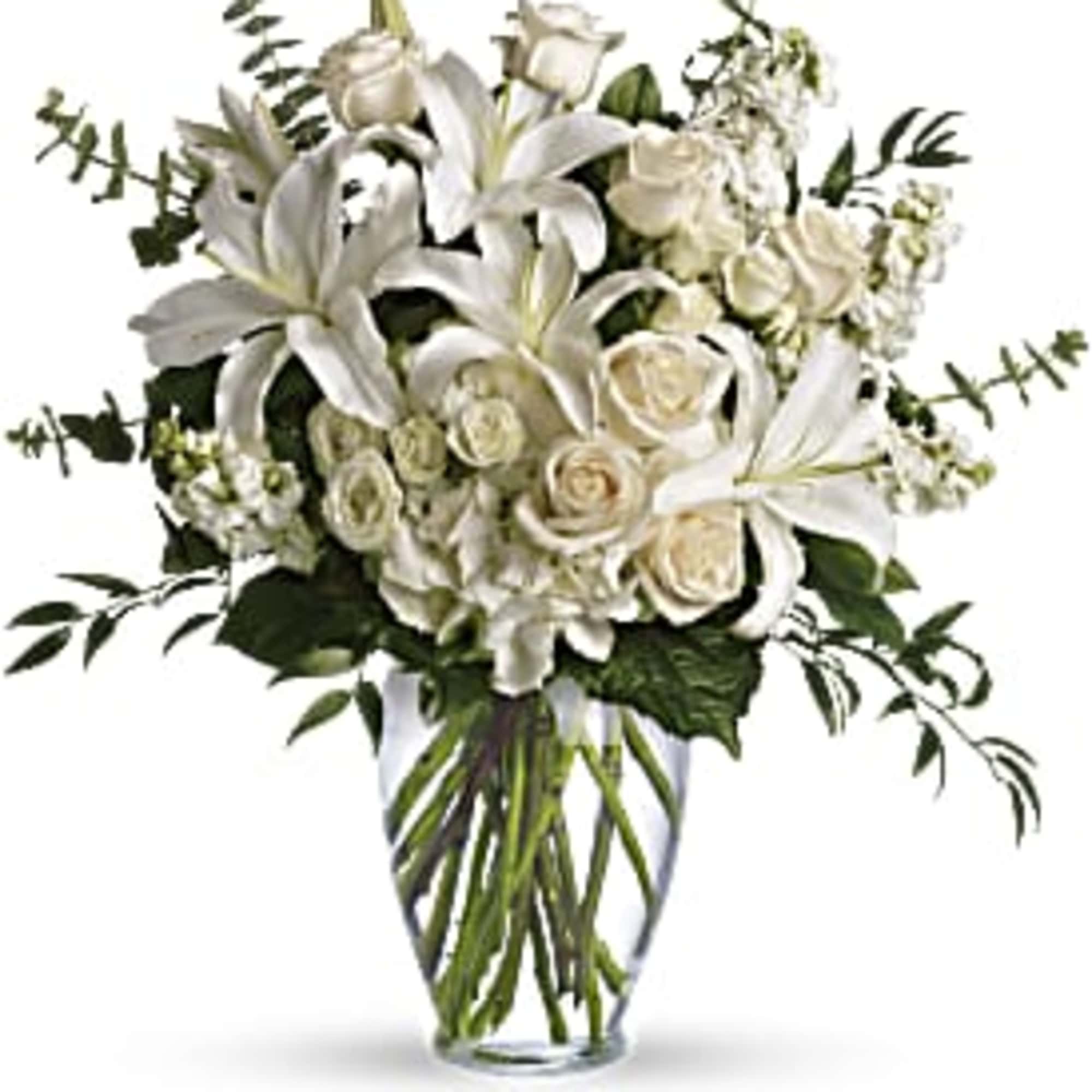 White lilies and roses arranged in a clear glass vase