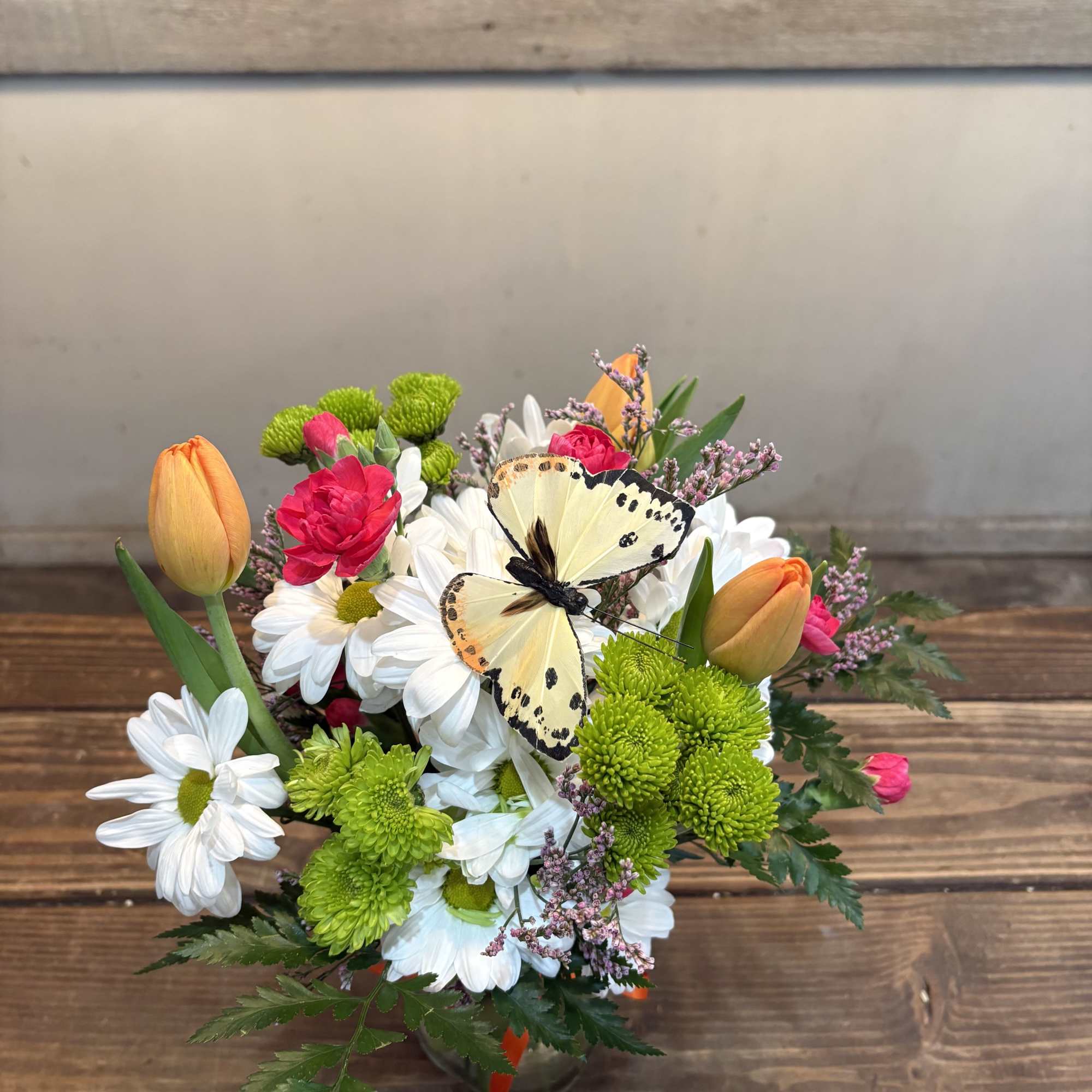 A cheerful cluster of orange tulips and crisp white daisies topped with