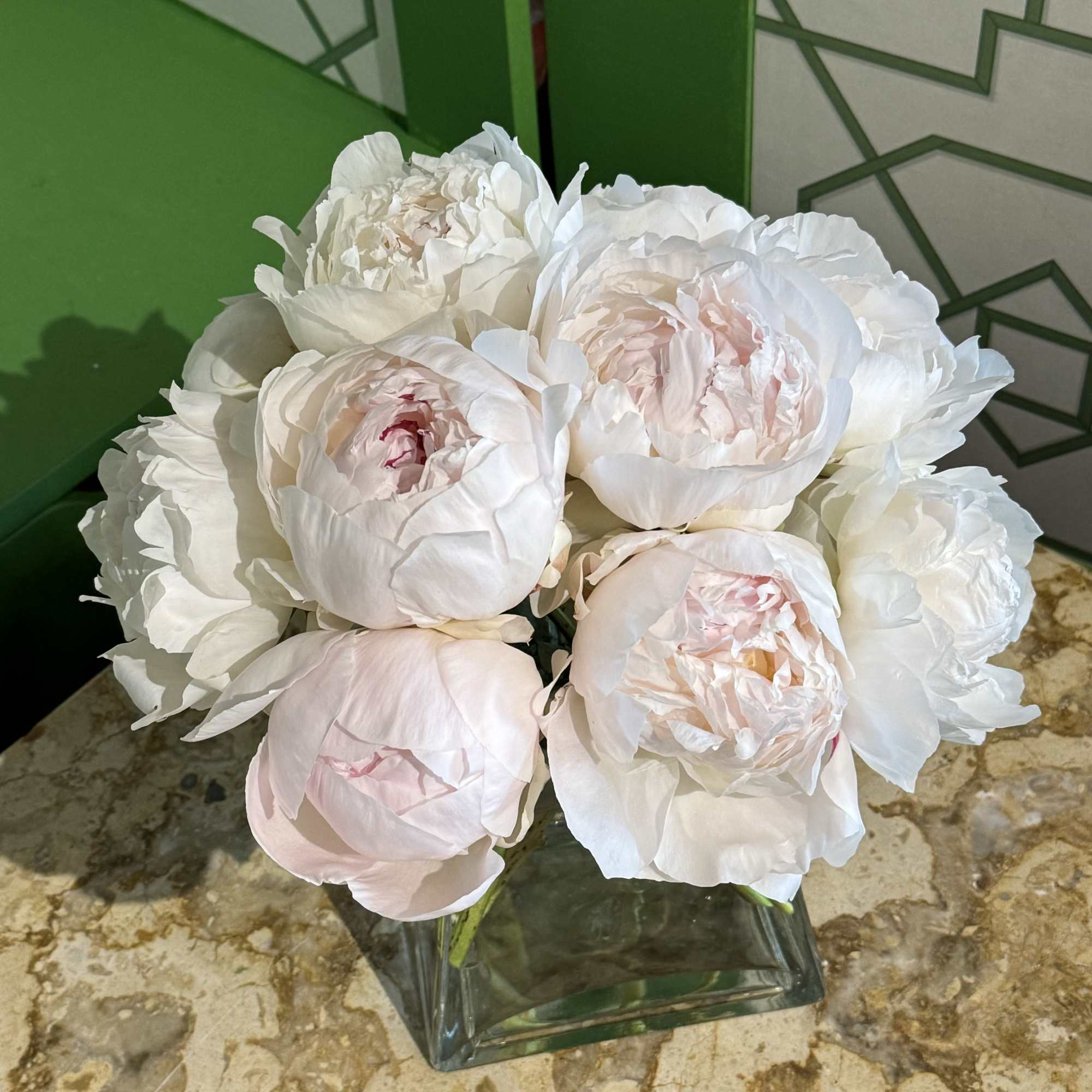 White and blush peonies arranged in a square glass vase