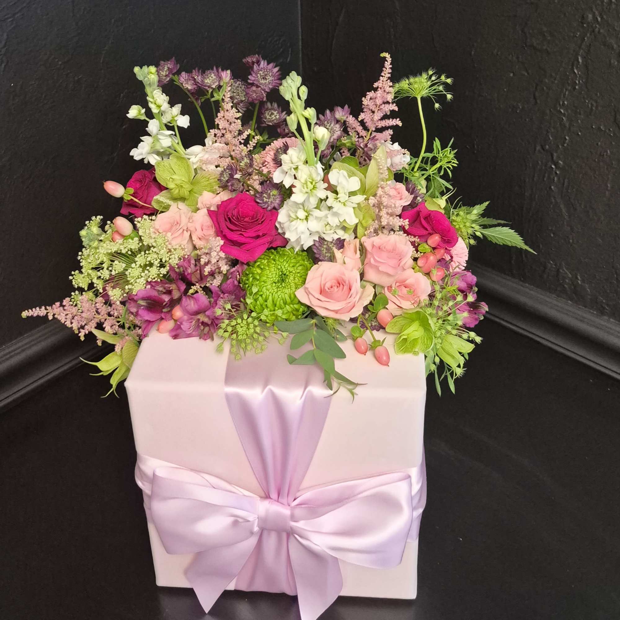 A dense cluster of blush and magenta roses with white stock and
