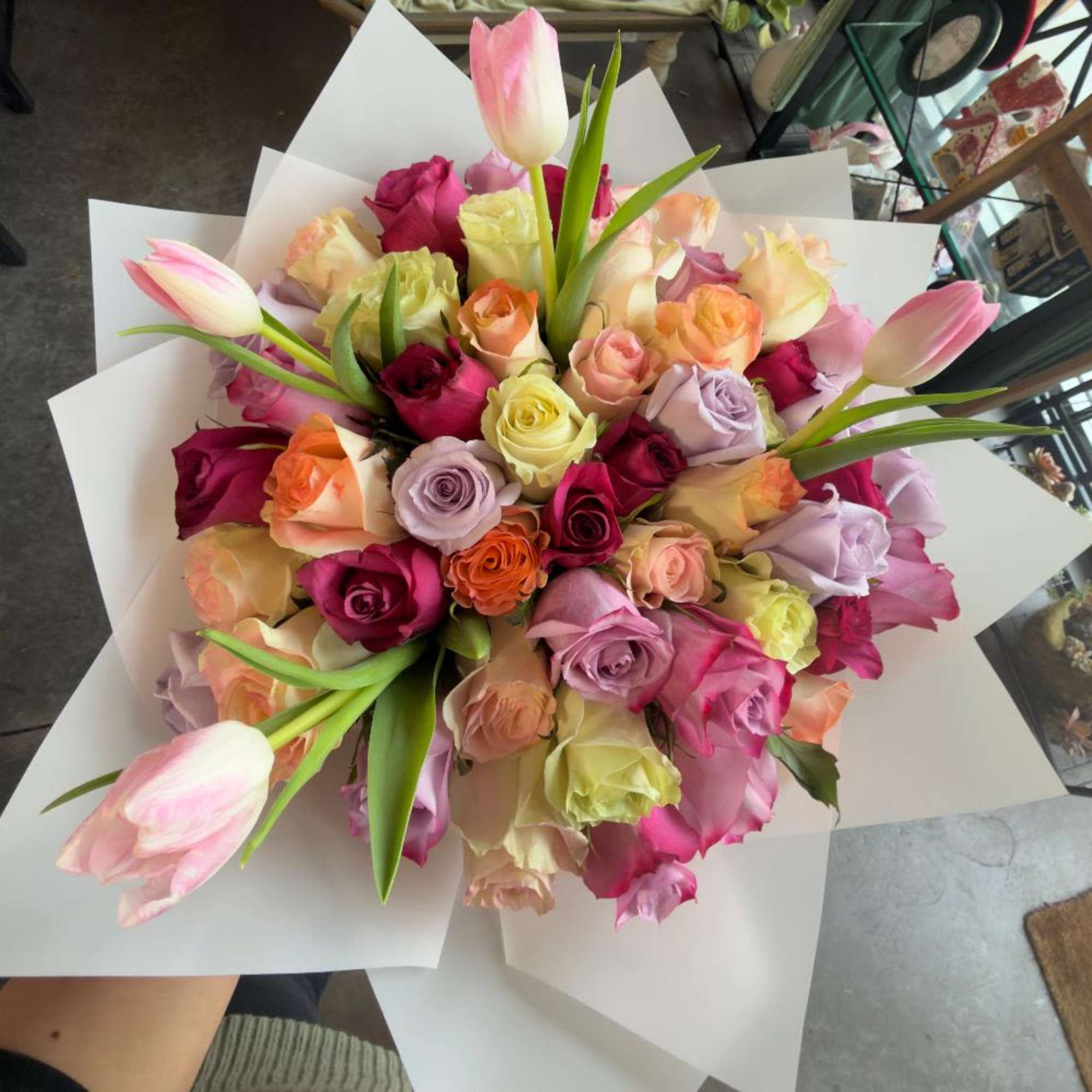 Bouquet of multicolored roses with pink tulips wrapped in white paper