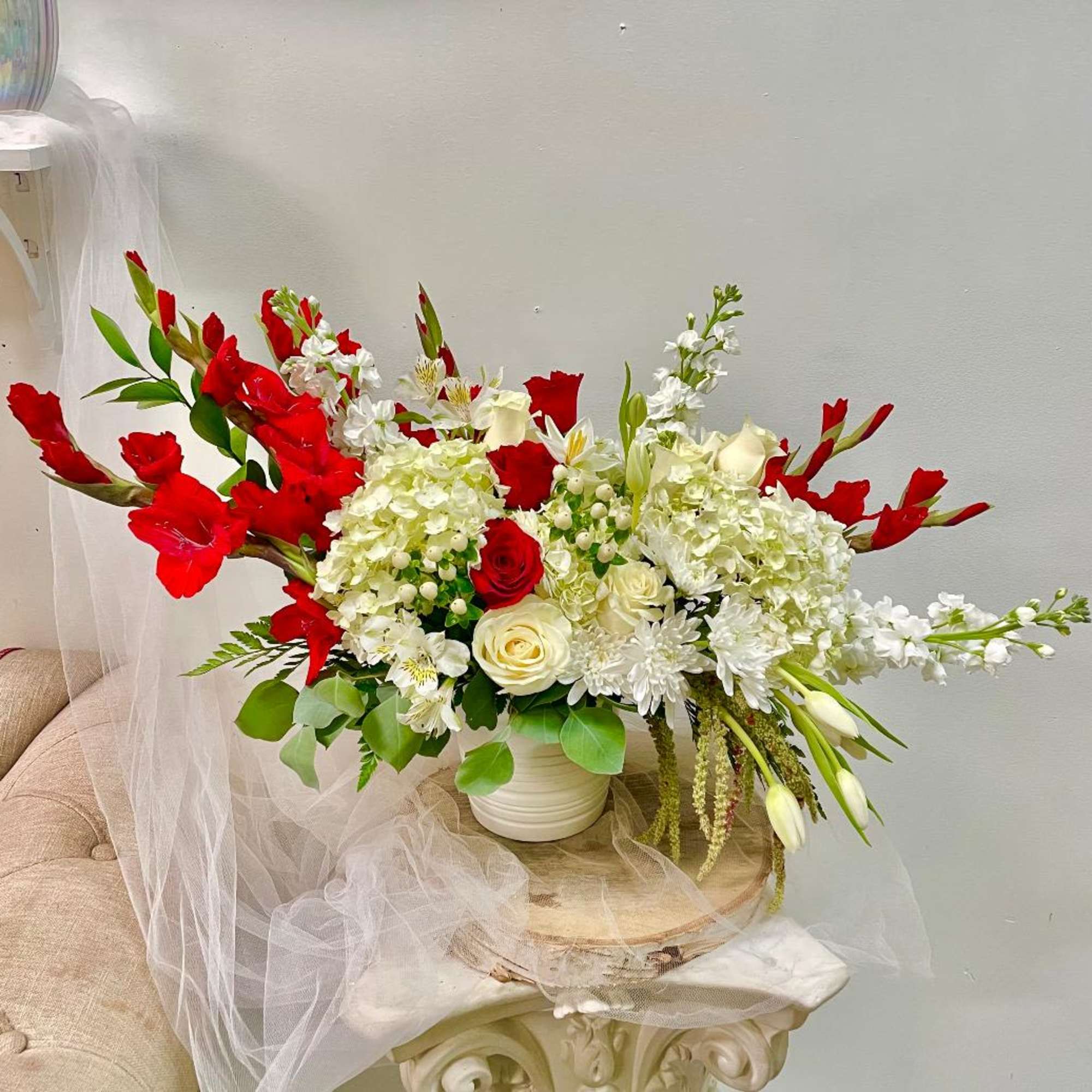 Large red and white floral arrangement in a white vase