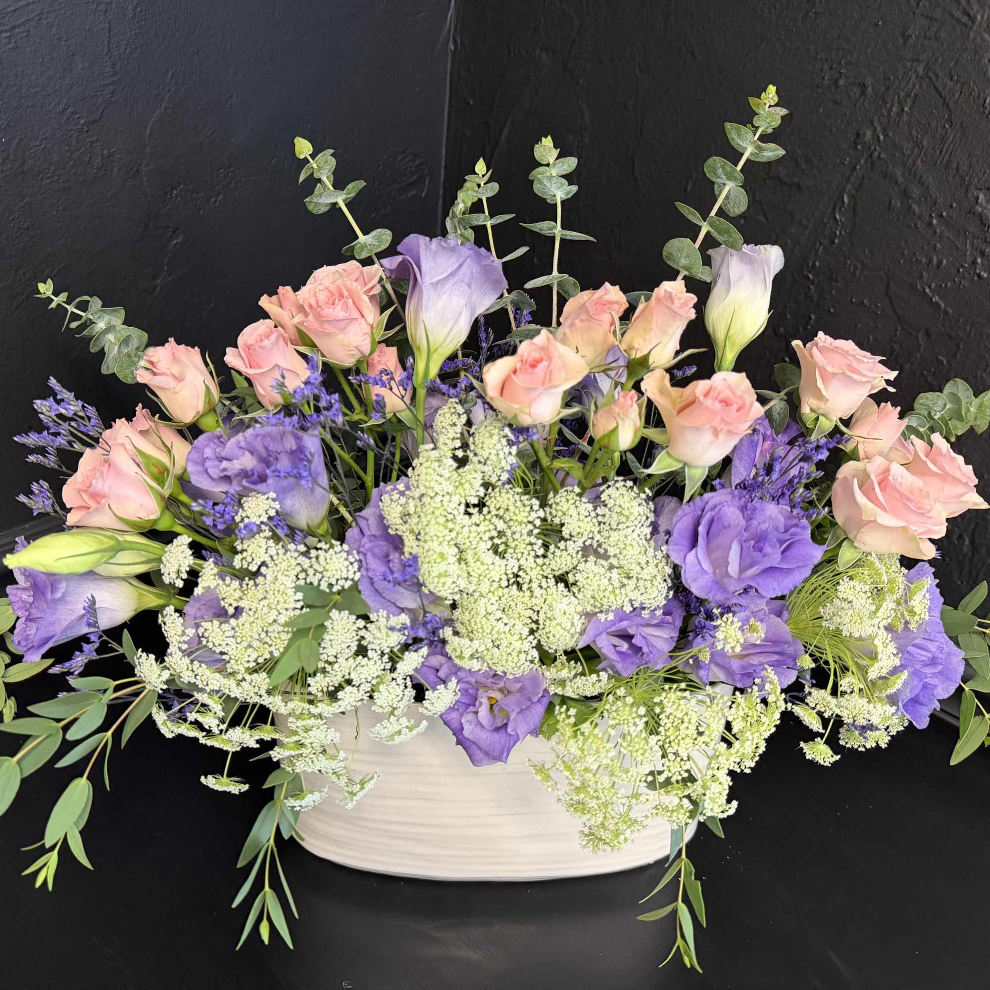 Soft lavender and blush pink blooms mingle in a low, wide composition