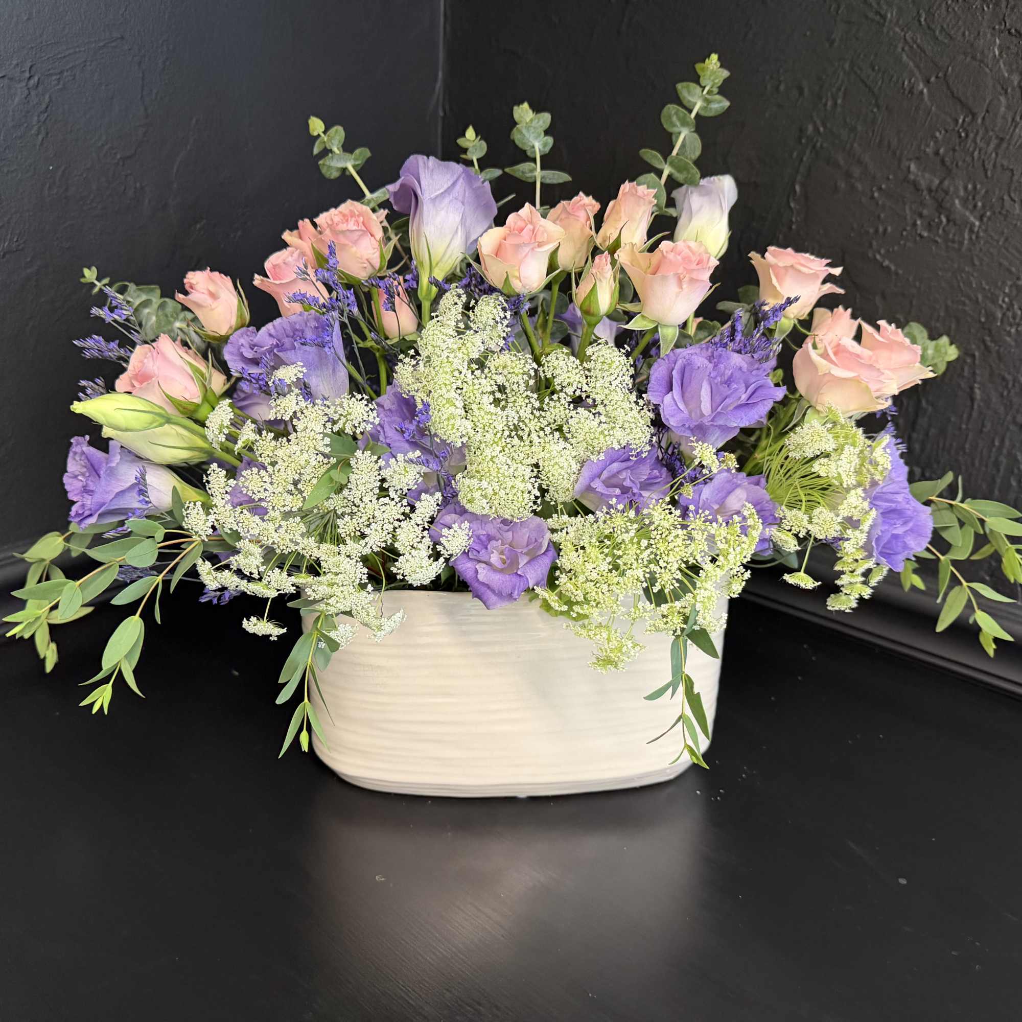 Soft lavender and blush pink blooms mingle in a low, wide composition
