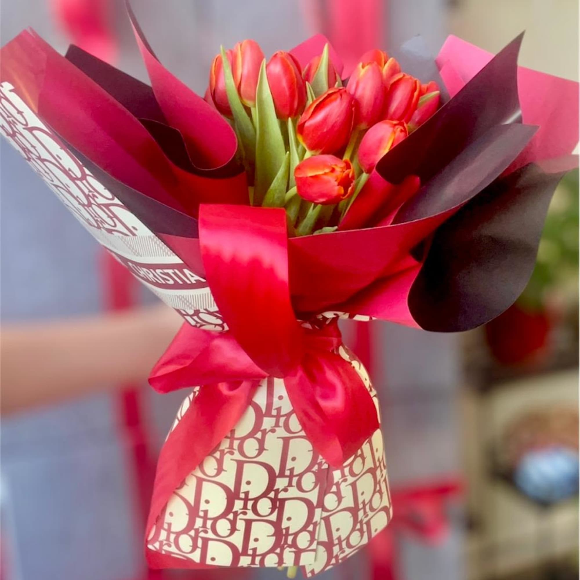 Bouquet of red tulips wrapped in pink and burgundy paper with a satin ribbon