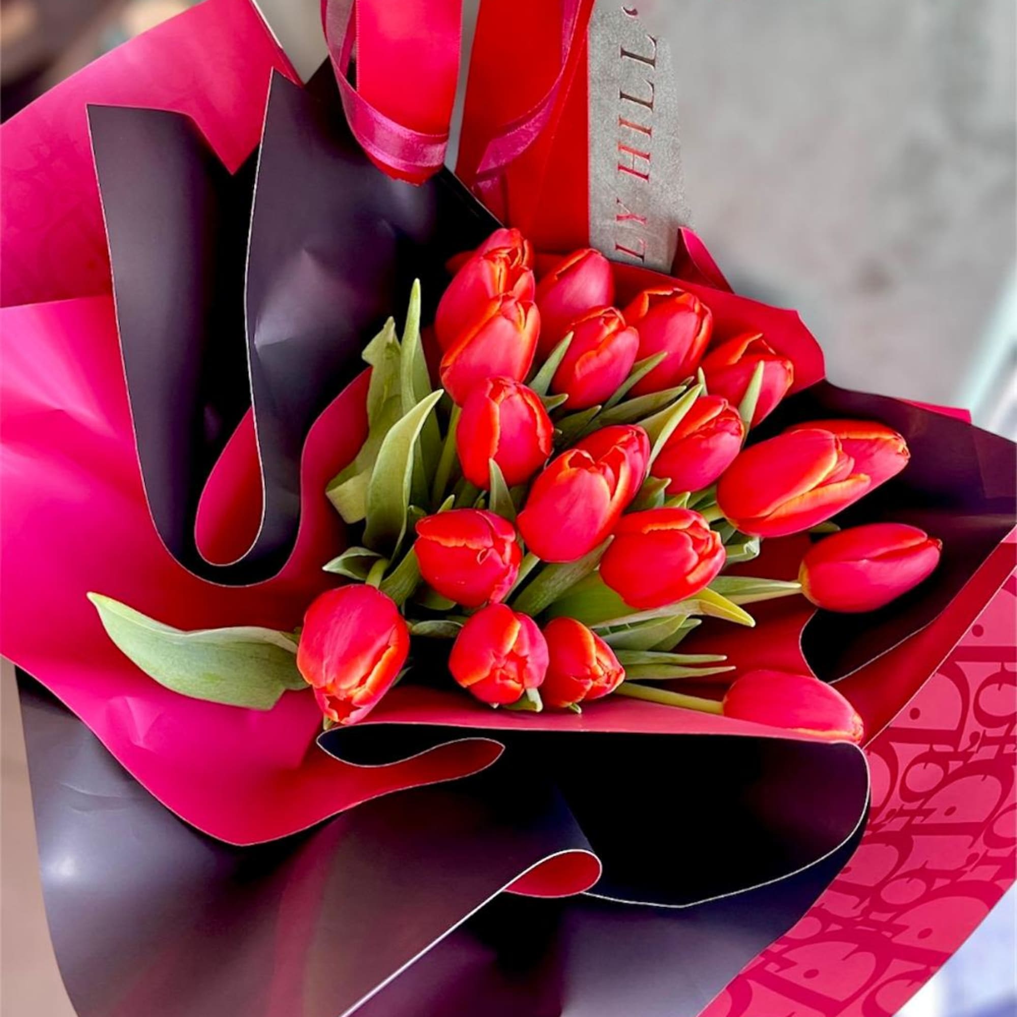 Bouquet of red tulips wrapped in pink and black paper