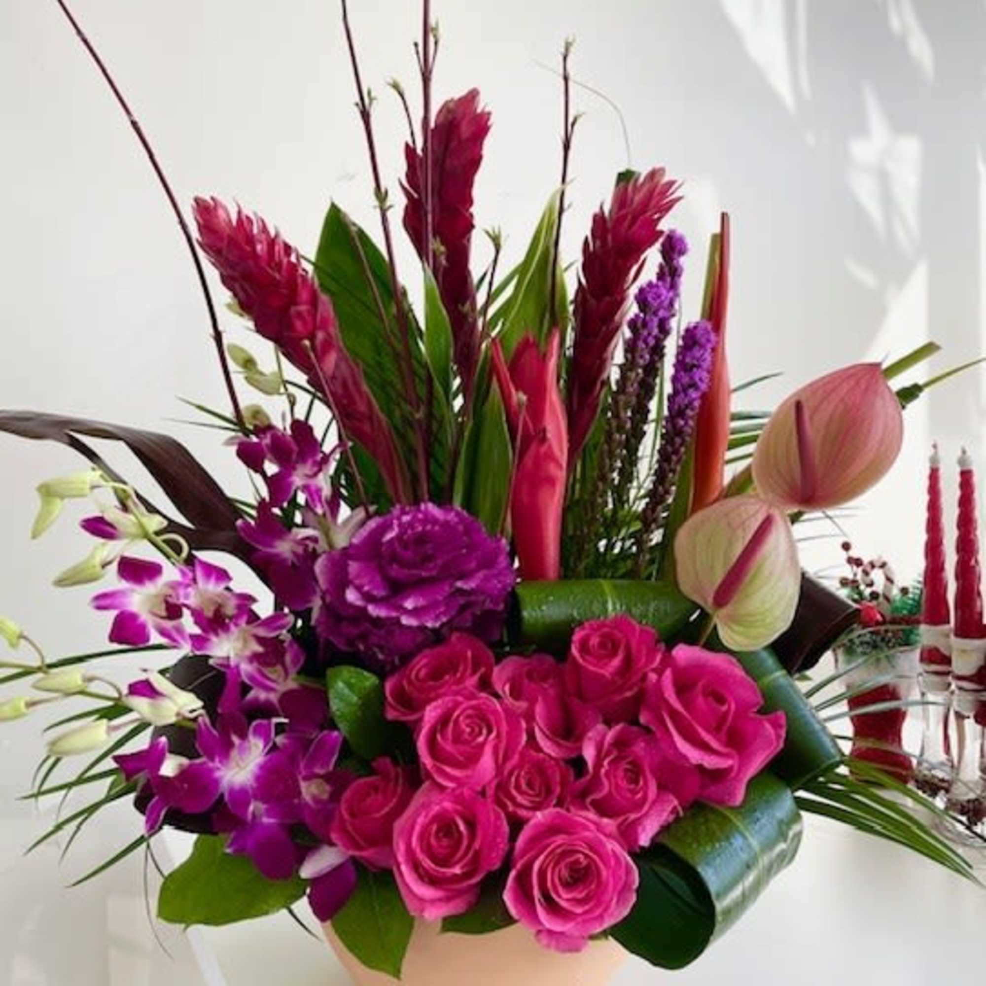 Pink roses and purple orchids arranged in a low vase
